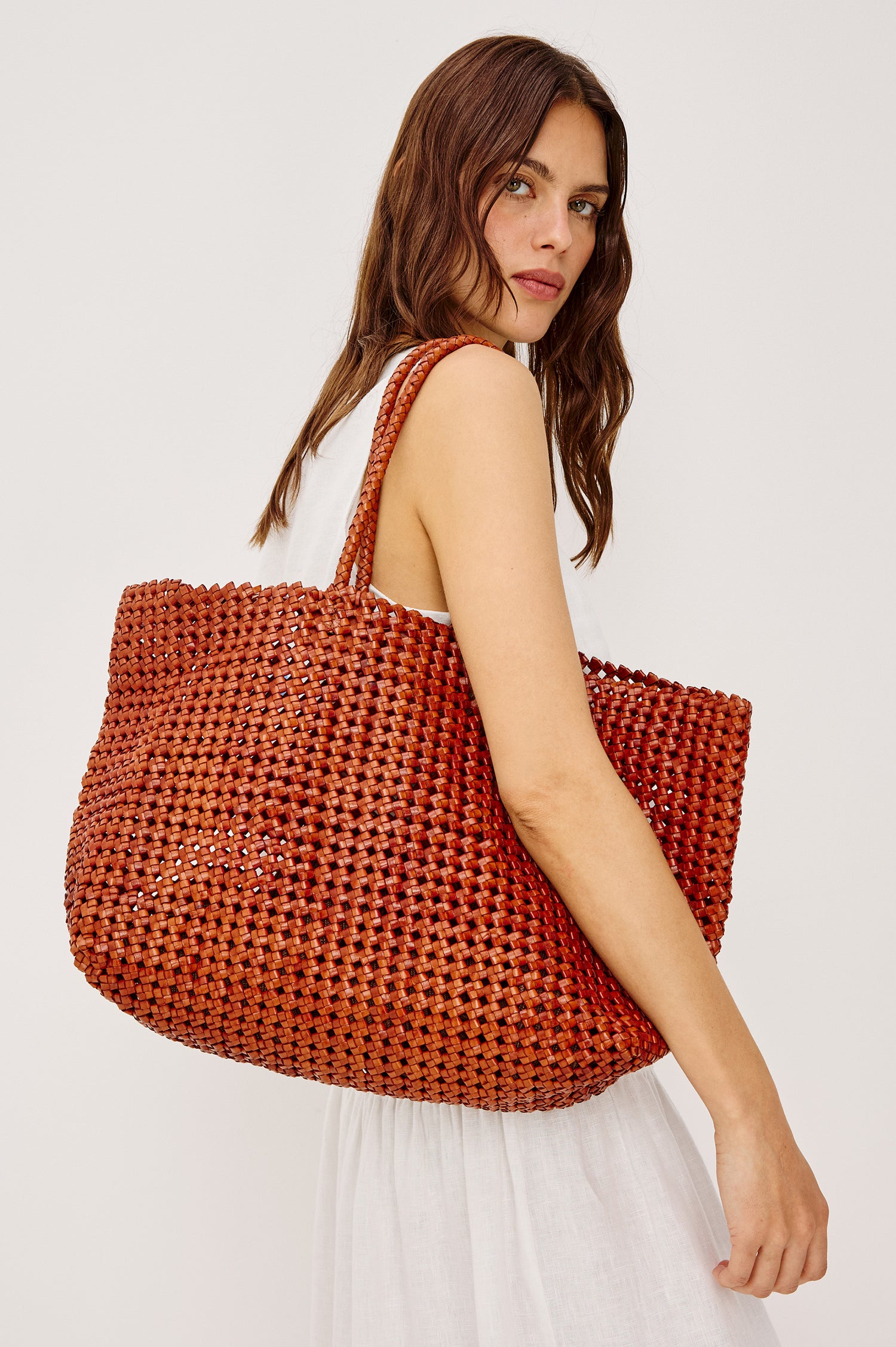 Brava oversized woven tote bag in Cognac brown - front view of model with bag over shoulder