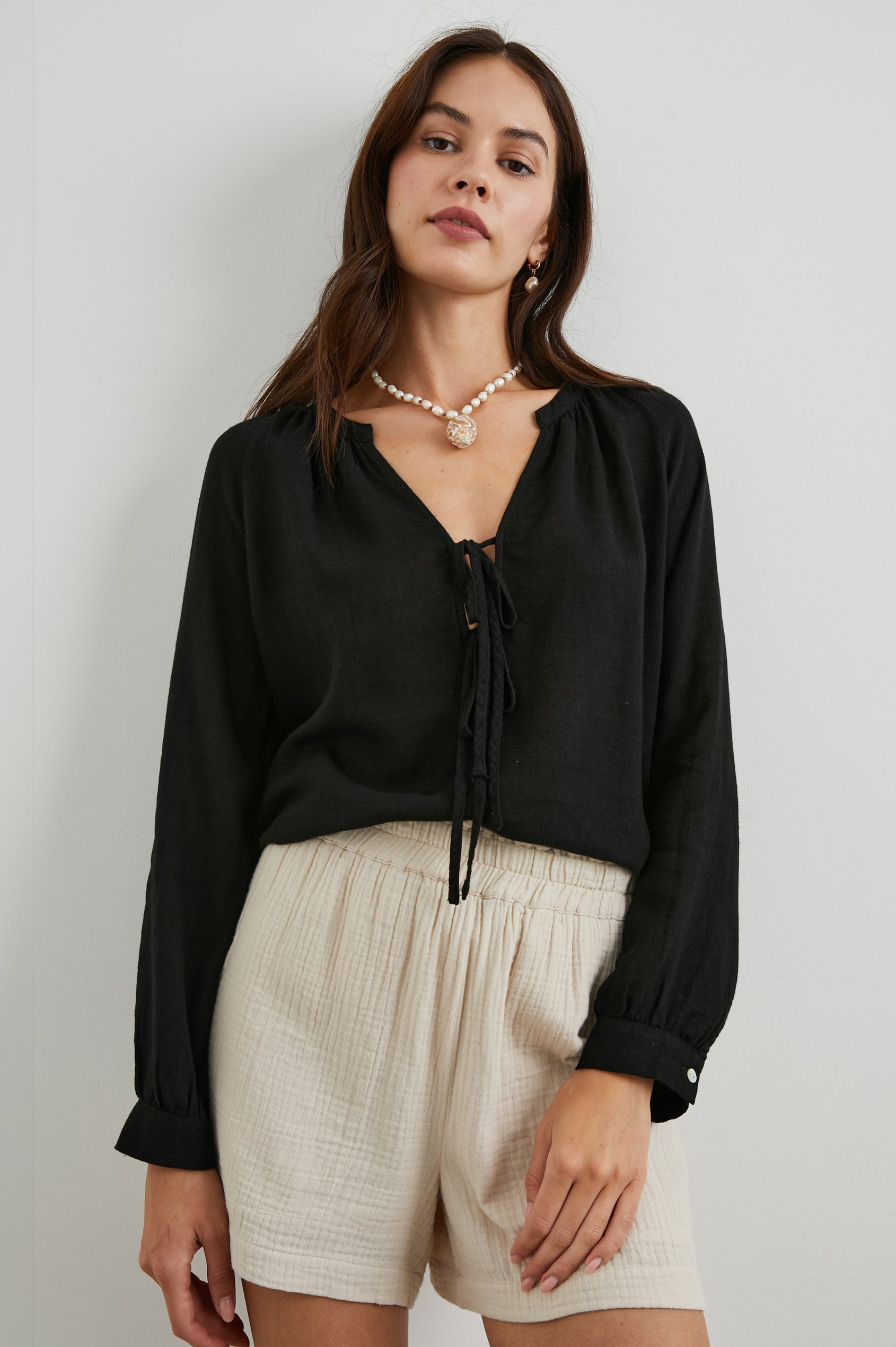 Brielle Long-Sleeve Top with a Deep V Neck with Ties and Pleats around the Neckline in Black Colorway - Front View Featured on Model