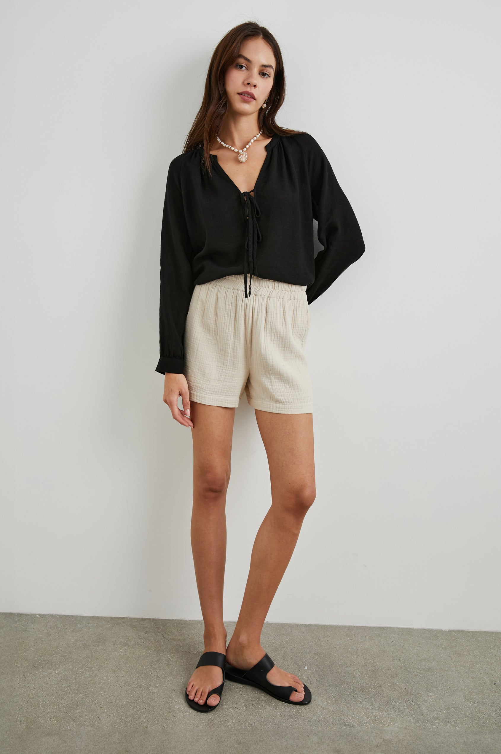 Brielle Long-Sleeve Top with a Deep V Neck with Ties and Pleats around the Neckline in Black Colorway - Front Full Body View Featured on Model