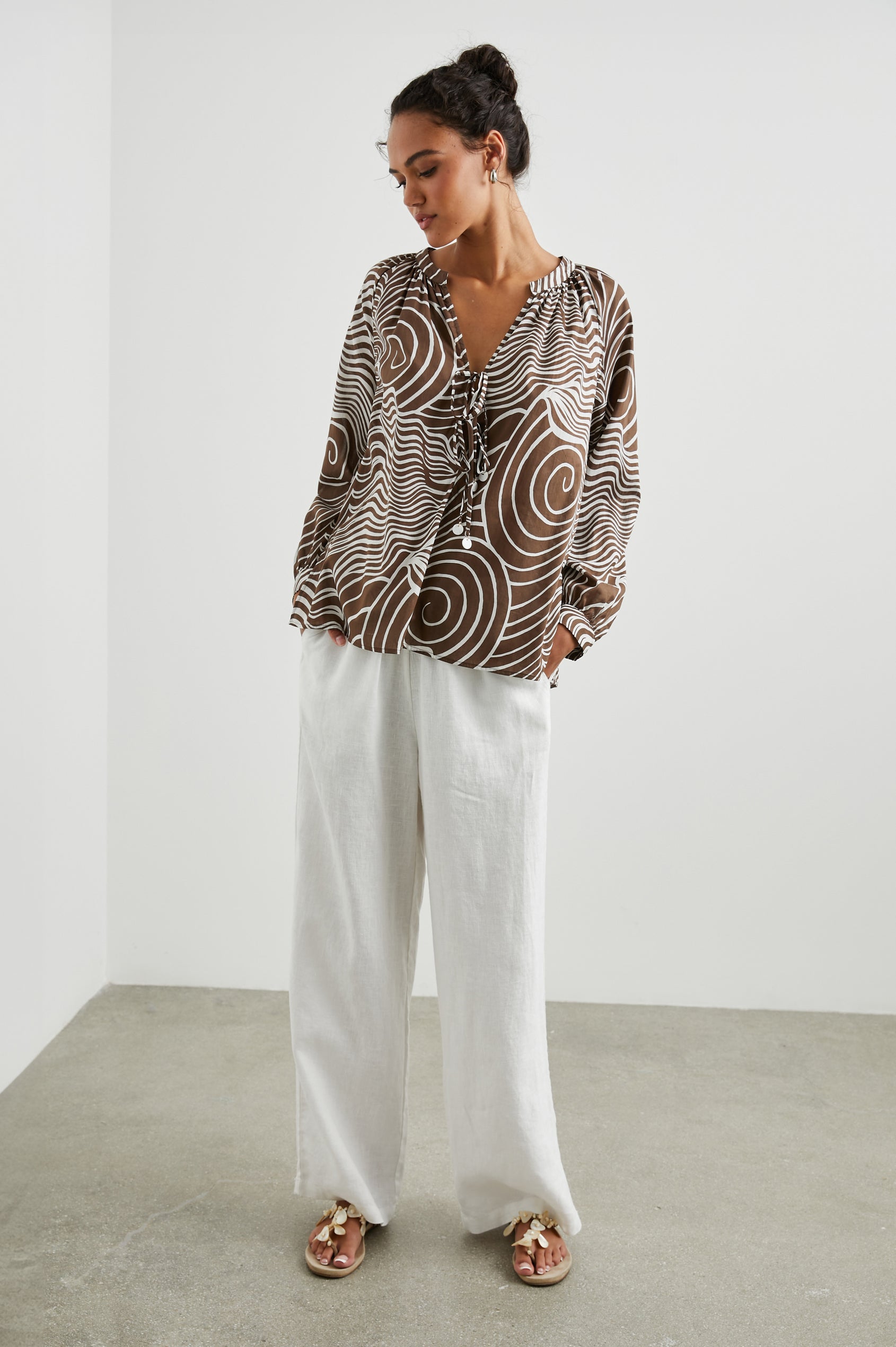 Brielle Long-Sleeve Top with a Deep V Neck with Ties and Pleats around the Neckline in Swirls Colorway, with white swirls on brown - Front Full Body View Featured on Model