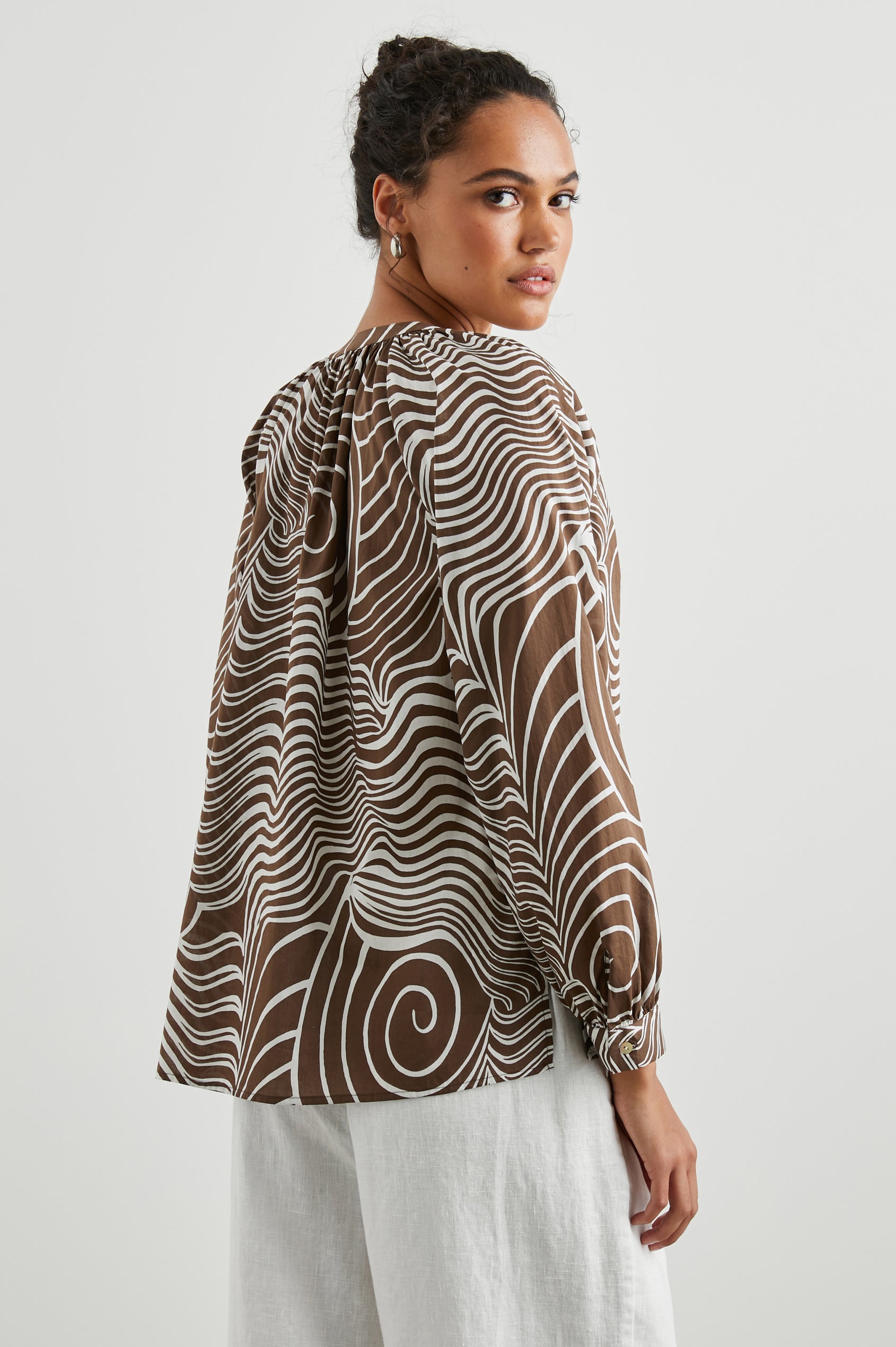 Brielle Long-Sleeve Top with a Deep V Neck with Ties and Pleats around the Neckline in Swirls Colorway, with white swirls on brown - Side View Featured on Model