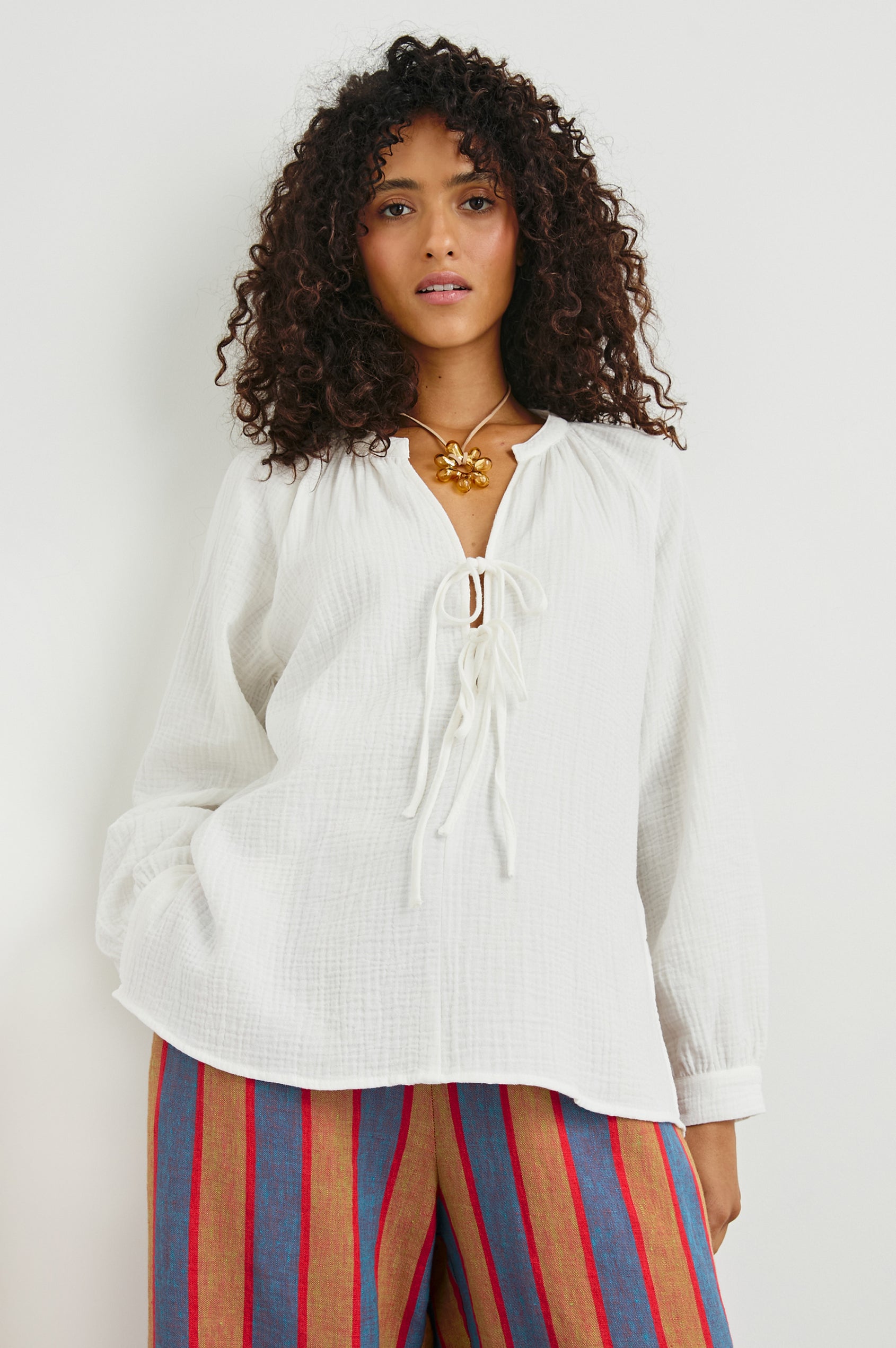 Brielle Long-Sleeve Top with a Deep V Neck with Ties and Pleats around the Neckline in White Colorway - Front View Featured on Model