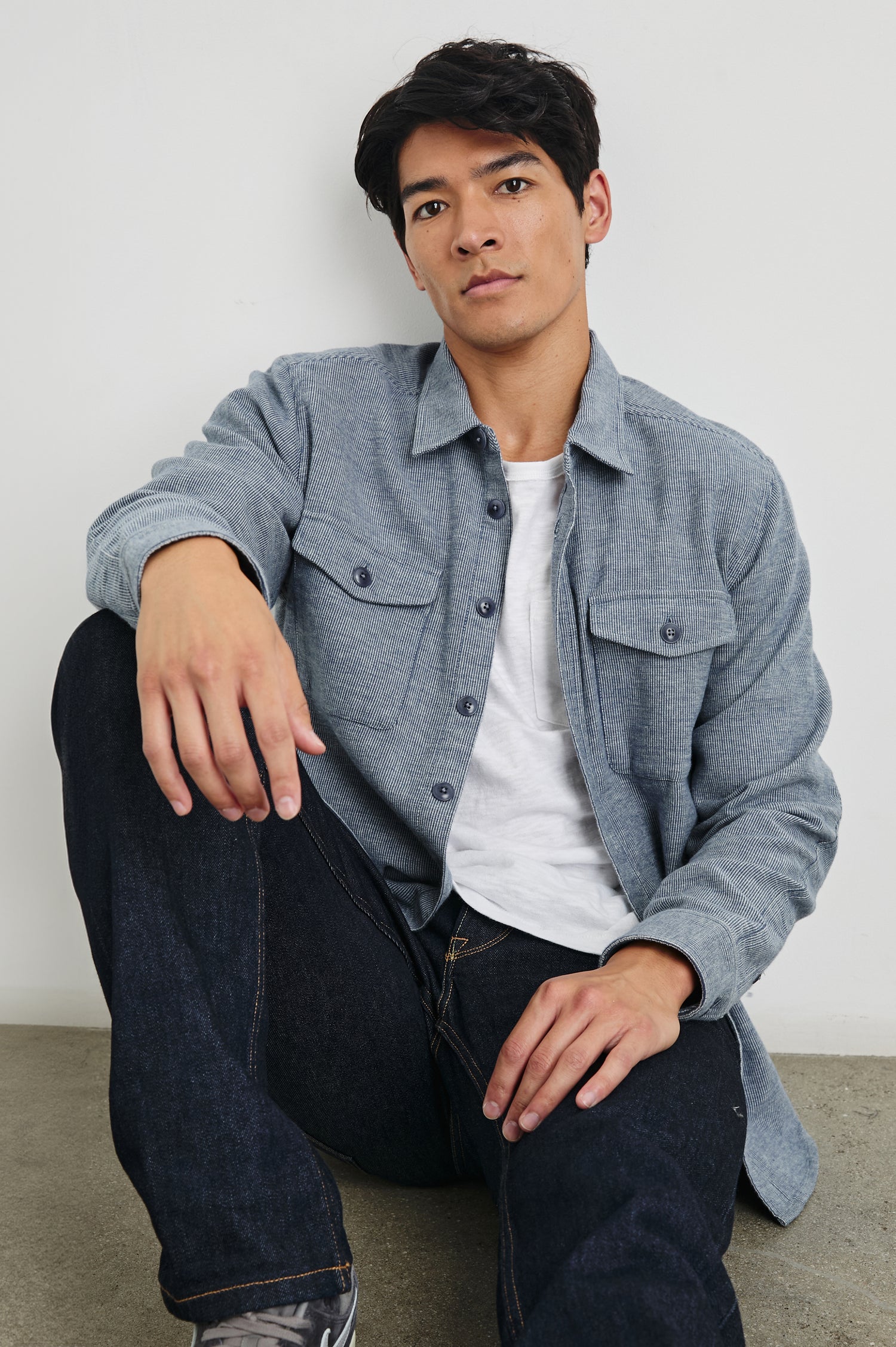 Burr Collared Shirt Jacket with Button Closure, Two Chest Button Flap Pockets and Textured Fabric in Denim White Colorway - Front Unbuttoned Full Body View Featured on Seated Model