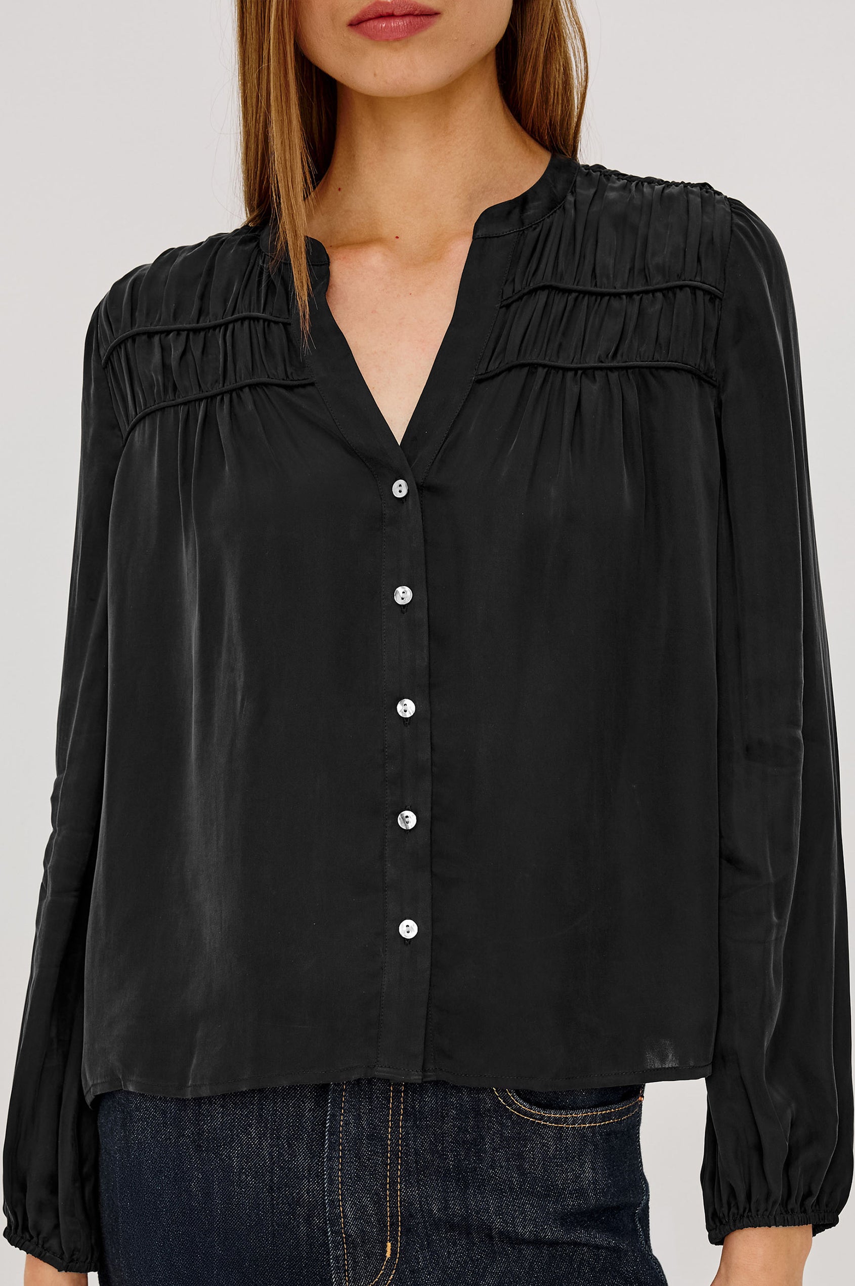 Cadence Shirt in Silky Fabric With Cutaway V-Neck, Shirred Yoke, Front Button Placket, and Slight Puff Long Sleeves and Elastic Cuffs in Black Colorway - Upper Body Front View Featured on Model