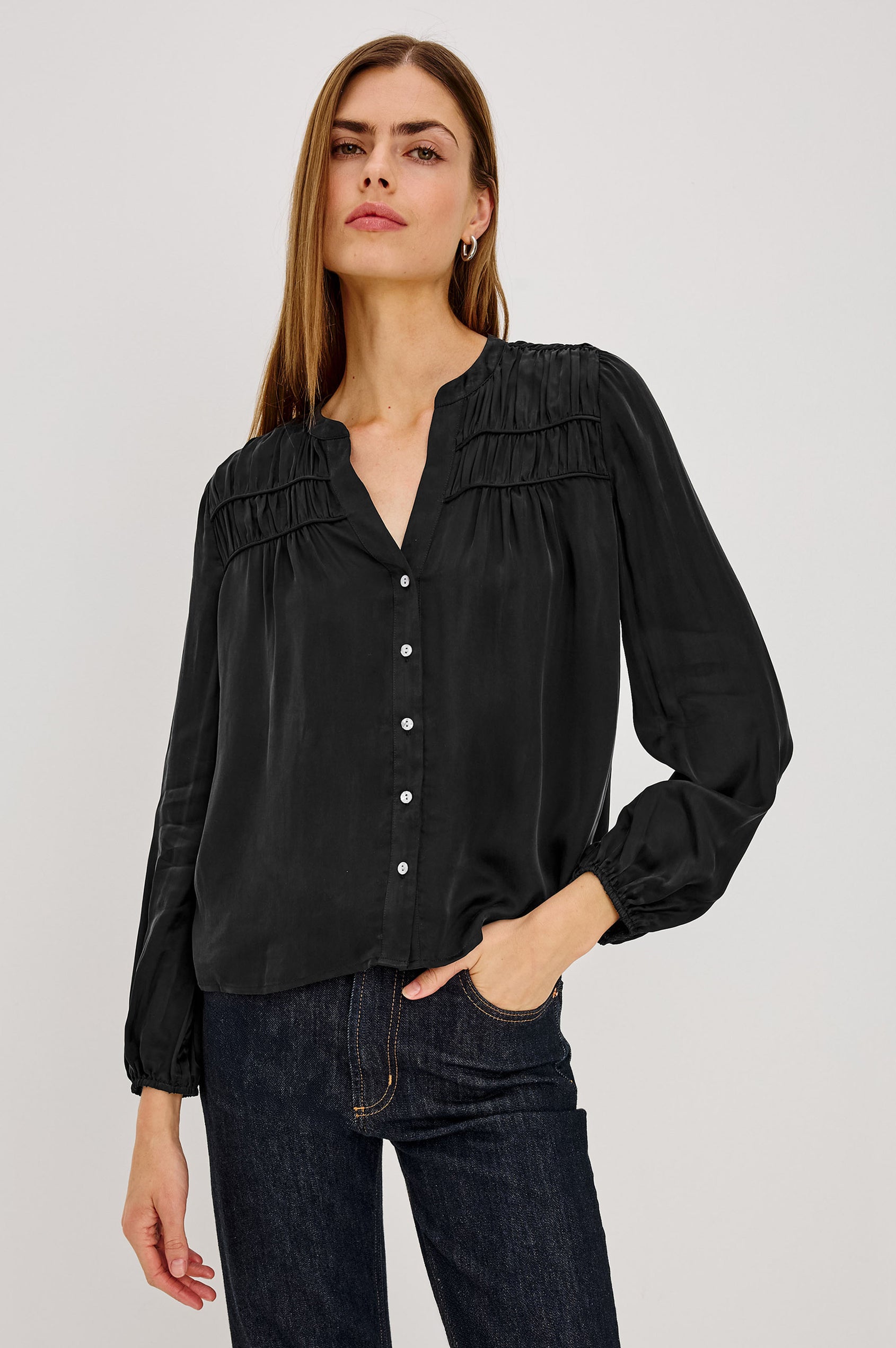 Cadence Shirt in Silky Fabric With Cutaway V-Neck, Shirred Yoke, Front Button Placket, and Slight Puff Long Sleeves and Elastic Cuffs in Black Colorway - Upper Body Front View Featured on Model