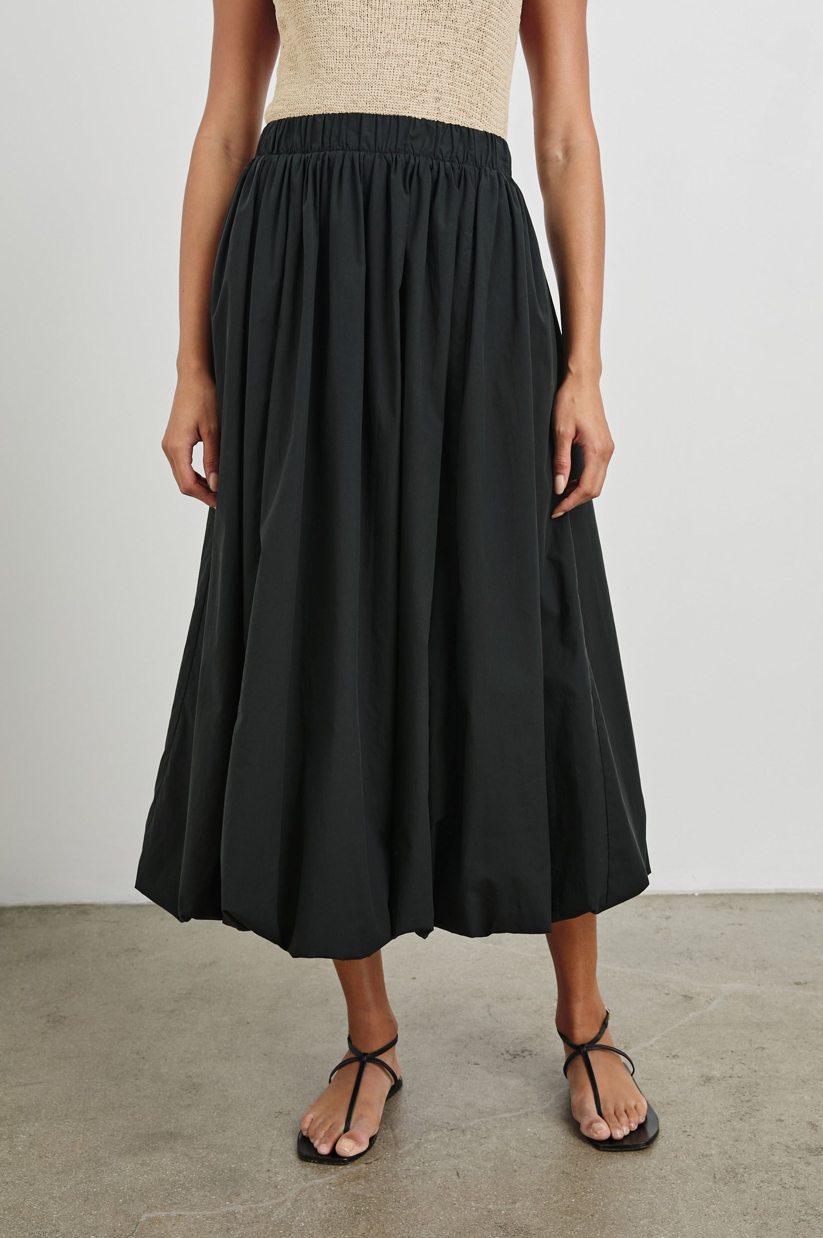 Cala midi length bubble skirt with elastic waistband and side pockets in Black - front view on model