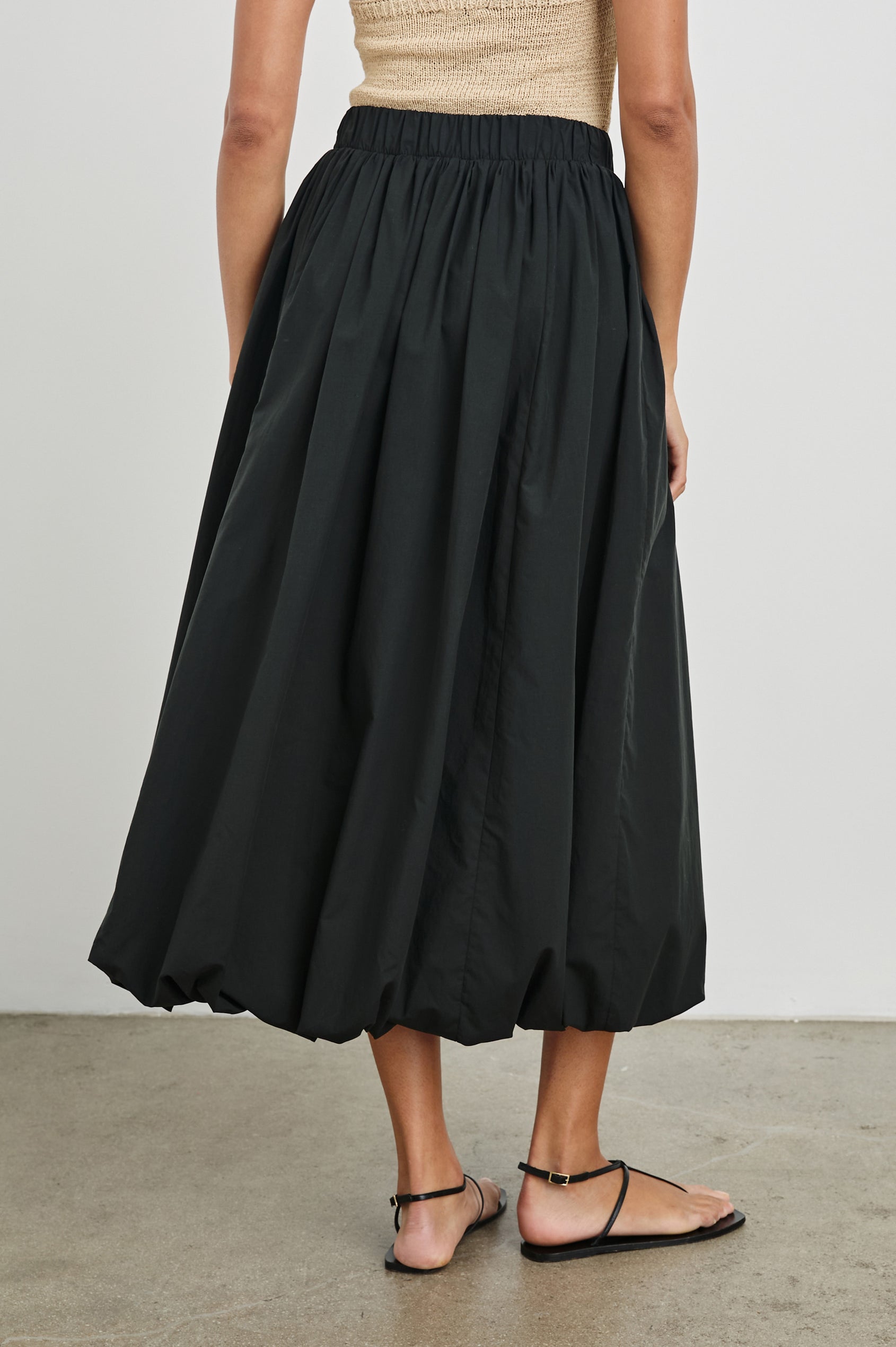 Cala midi length bubble skirt with elastic waistband and side pockets in Black - back view on model 