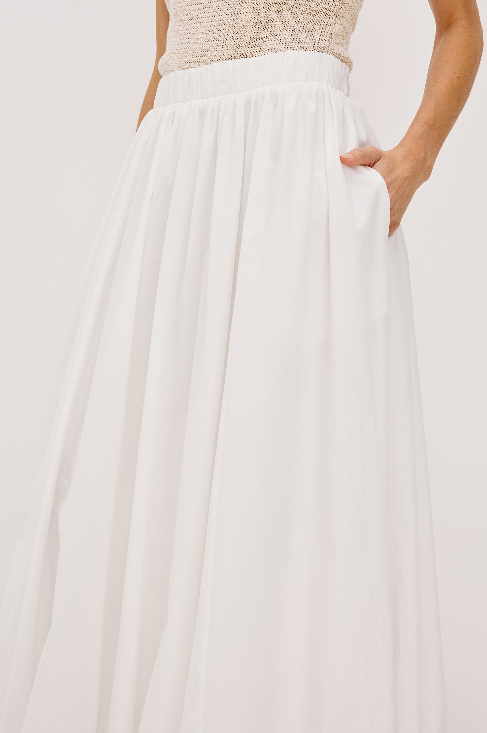 Cala midi length bubble skirt with elastic waistband and side pockets in White Colorway - front and side detail view on model.