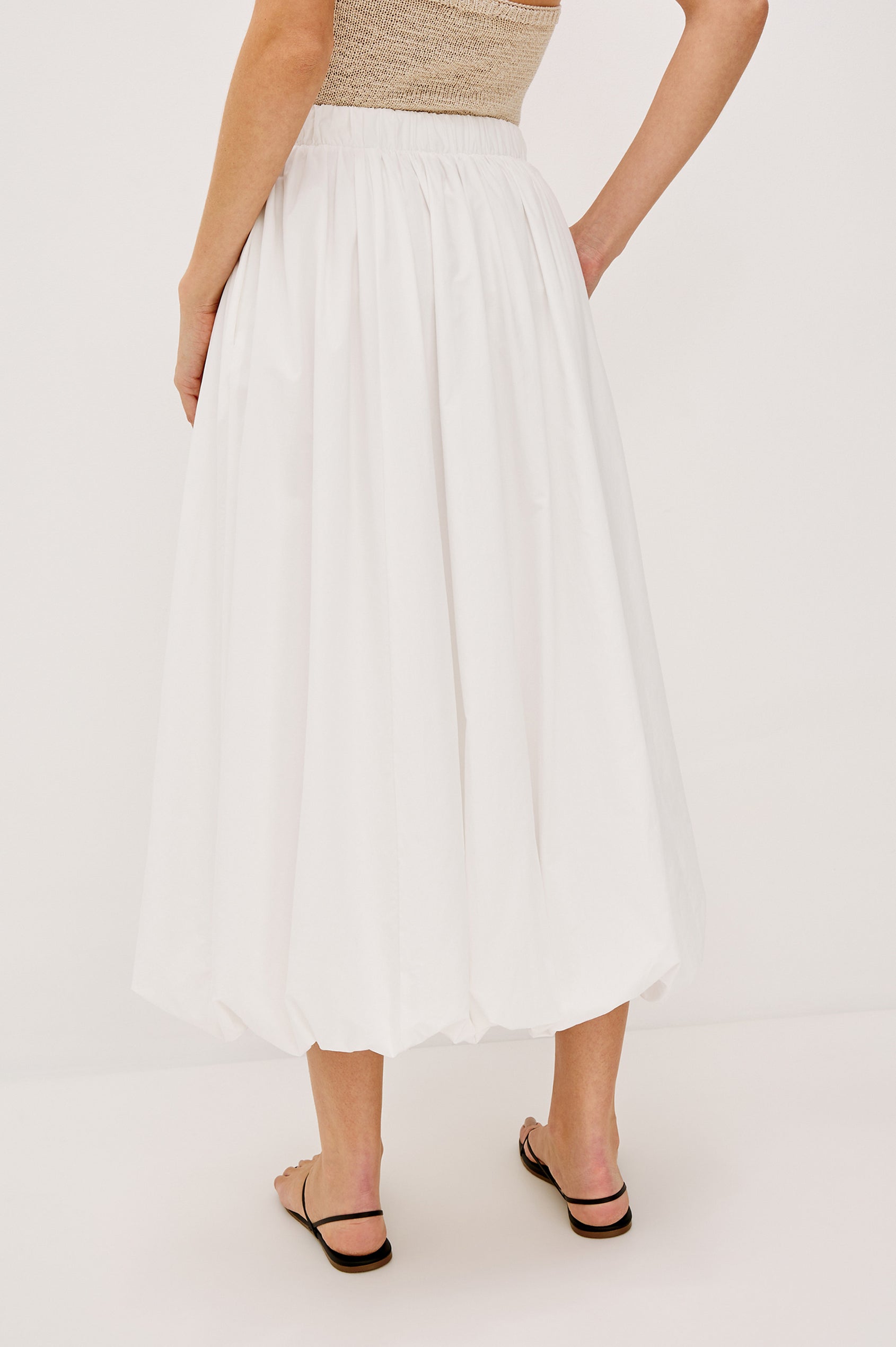 Cala midi length bubble skirt with elastic waistband and side pockets in White Colorway - back view on model.