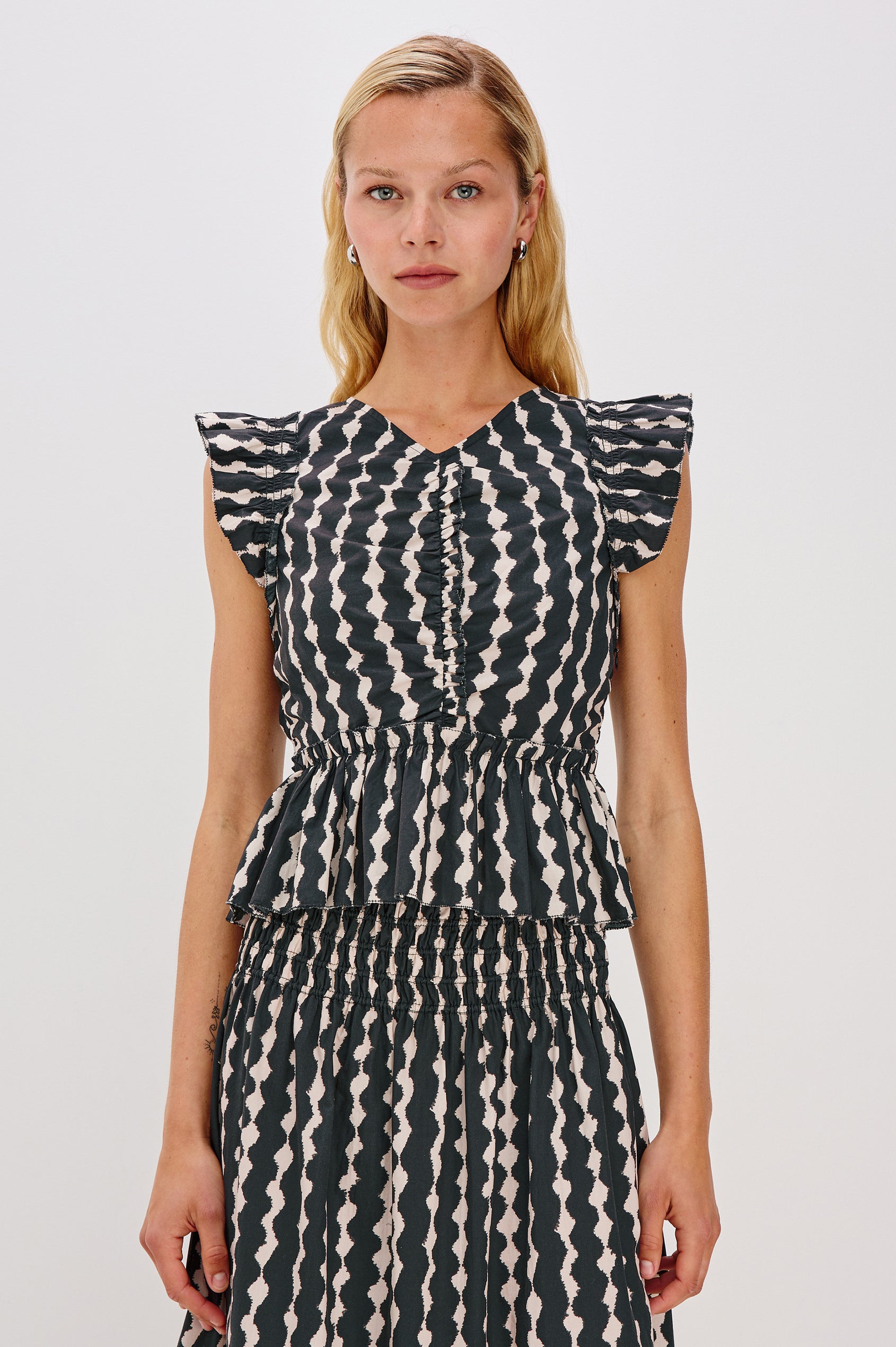 Cali short sleeve top with center front ruching, flutter sleeves, and a ruffle hem in Painted Noir colorway - front view on model