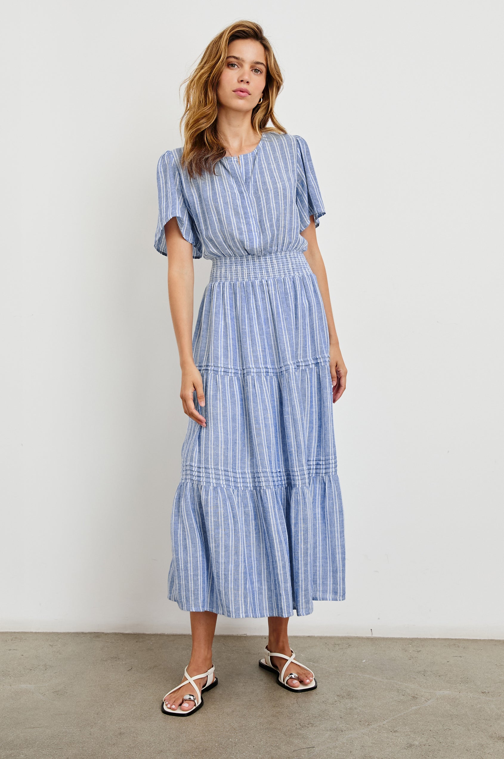 Cannes Short-Sleeve Midi Dress with a Shirred Waist, Tiered Skirt and Short Slit at Neck in Lake View Stripe Colorway, vertical stripes in blues and white - Front Full Body View Featured on Model