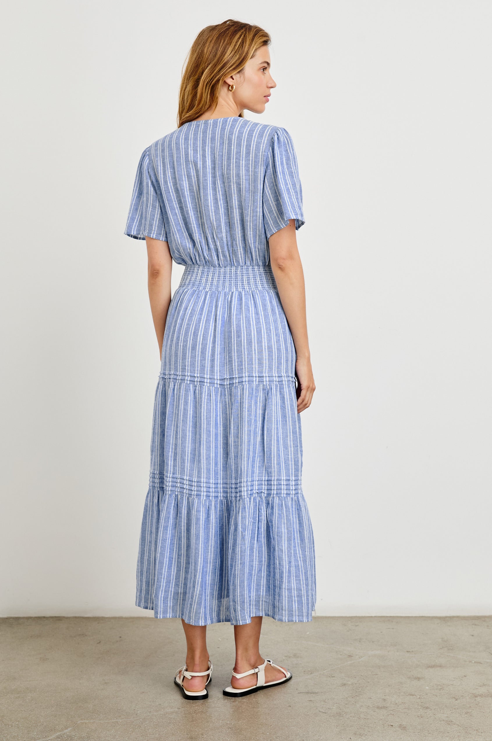 Cannes Short-Sleeve Midi Dress with a Shirred Waist, Tiered Skirt and Short Slit at Neck in Lake View Stripe Colorway, vertical stripes in blues and white - Back Full Body View Featured on Model