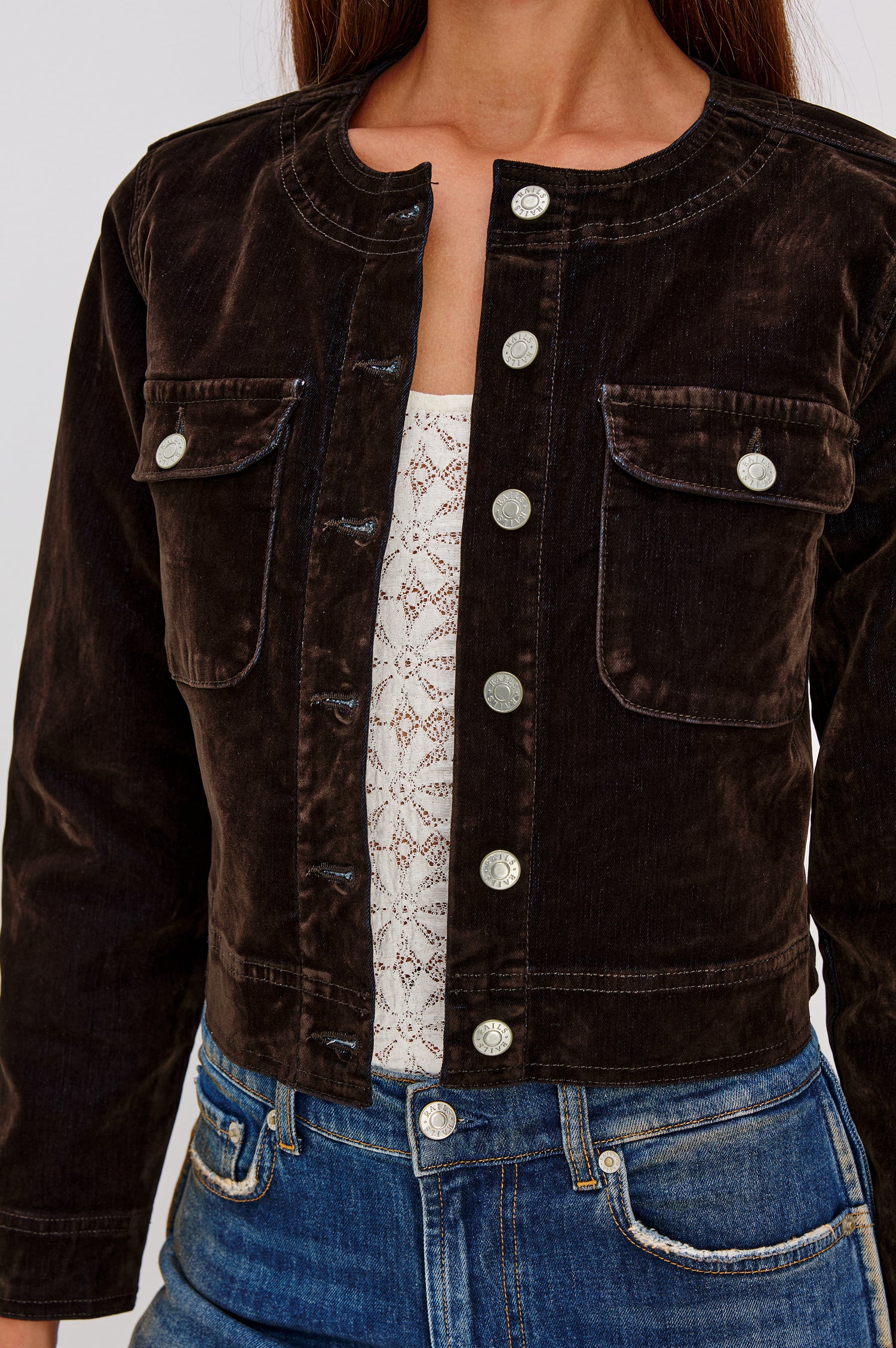 Capistrano Cropped Jacket in Chocolate Velvet Flocked Denim With Crew Neckline, Indigo Wash, Front Buttons, Buttoned Chest Pockets, and Long Sleeves in Chocolate Flocking Colorway - Upper Body Front Close Up View Featured on Model