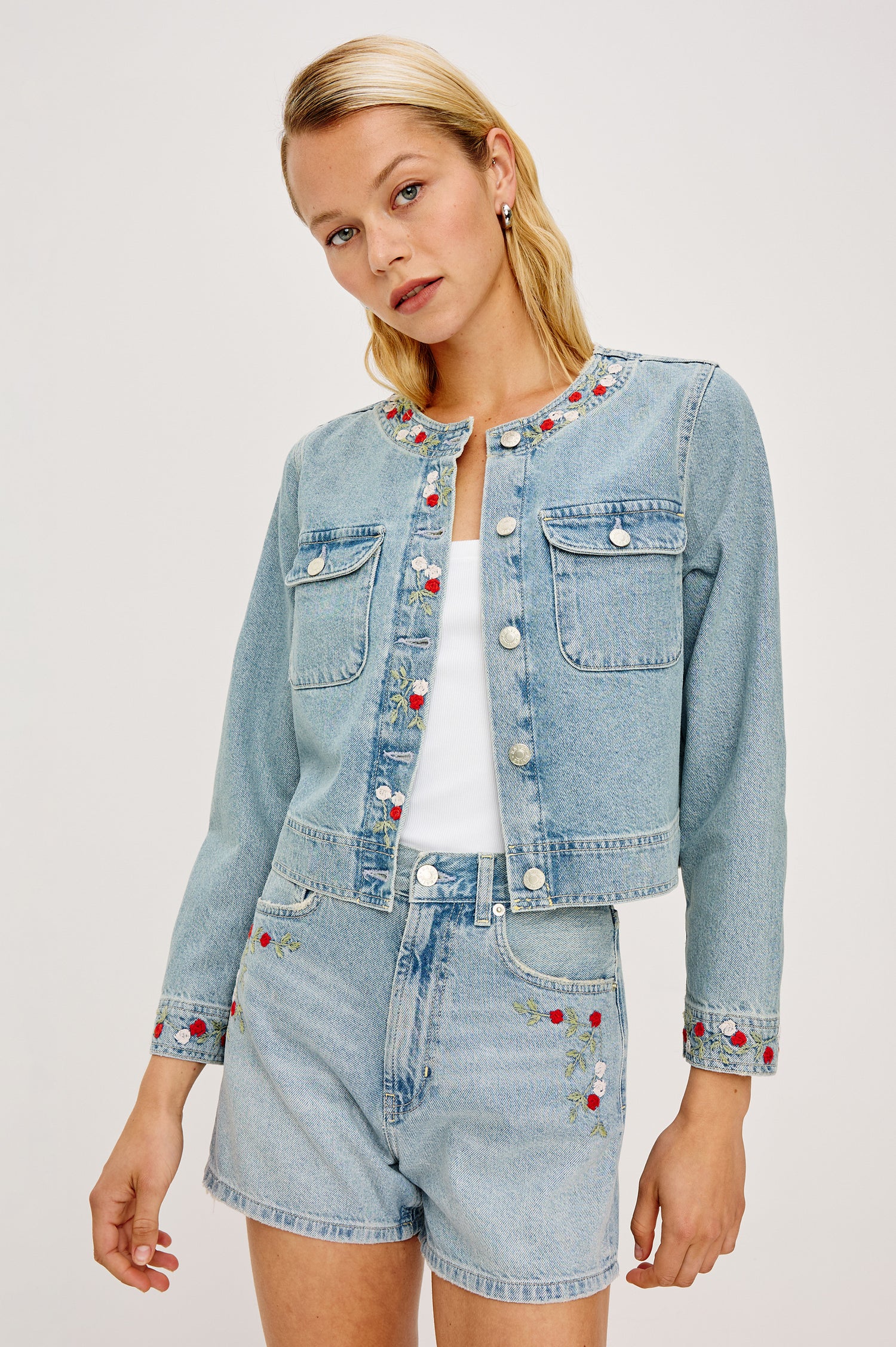 The Capistrano is a cropped denim jacket with a scoop neck, a button front, two chest pockets in Floral laser colorway. Front view featured on model.