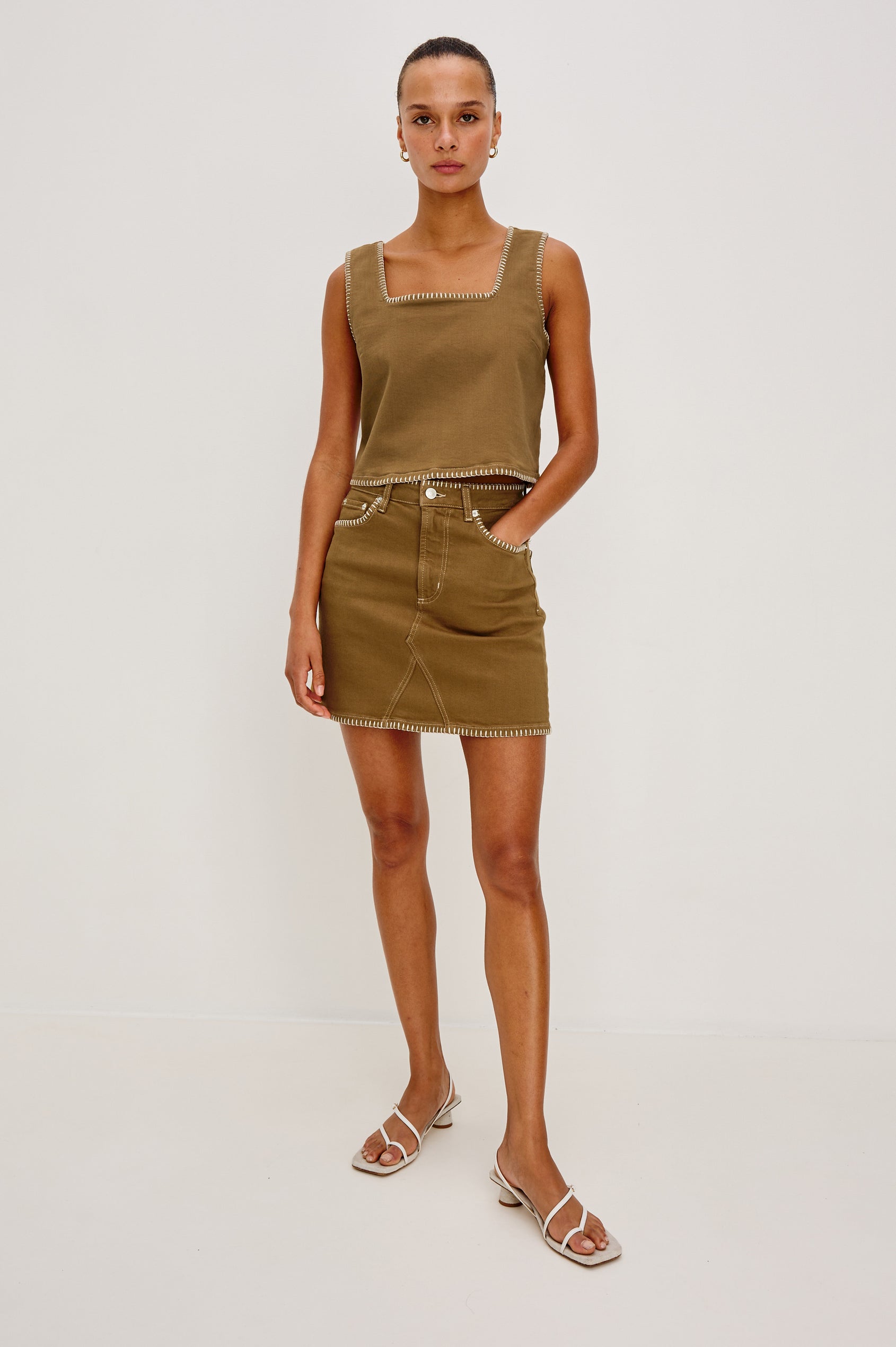 Laurel 5-Pocket Colored Denim Mini Skirt With Blanket Stitch Along All Edges in Safari Embroidered. Front View Shown on Model.