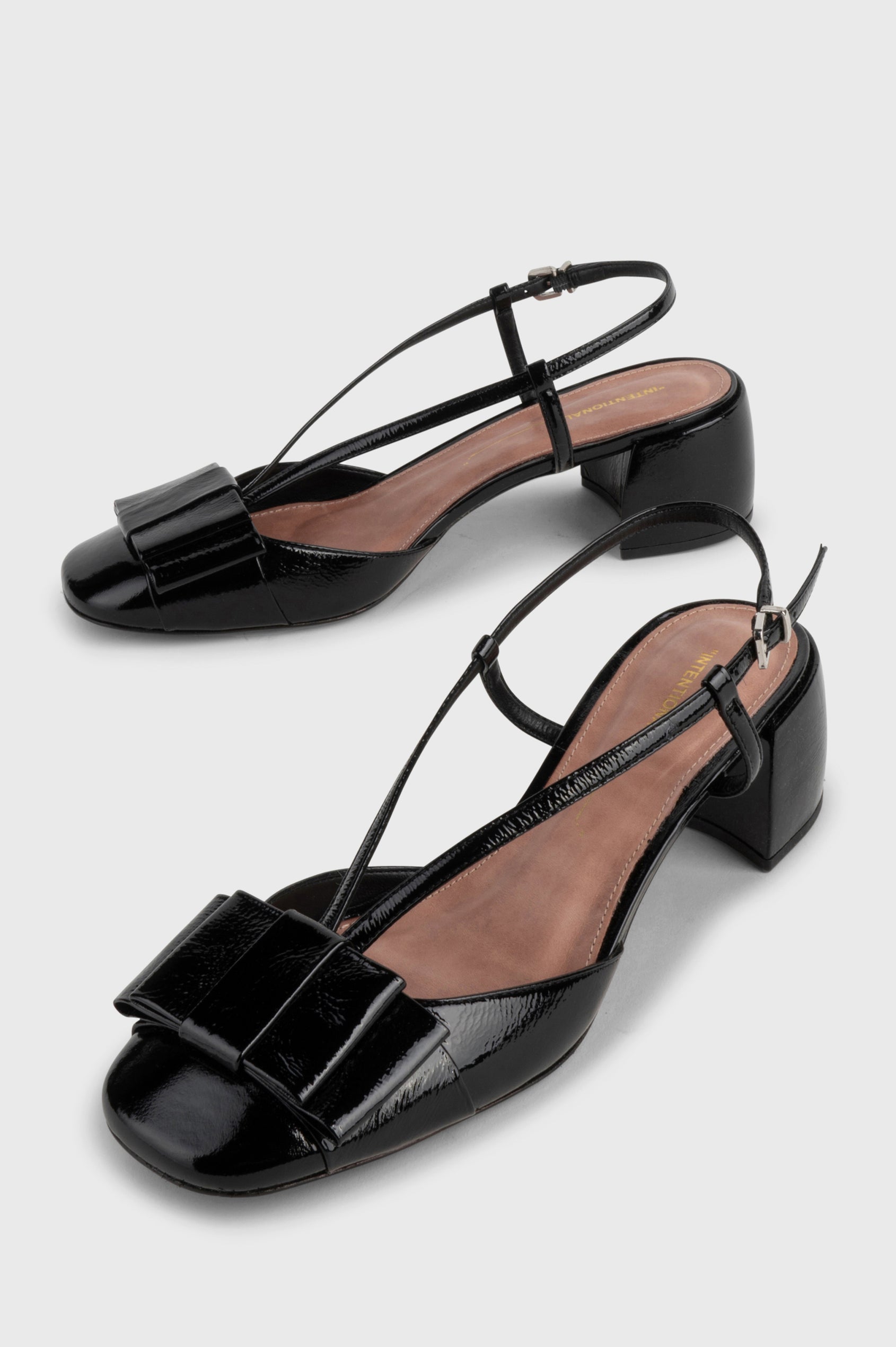 Carina patent leather heel with slingback straps, block heel and front leather bow in Black colorway - side angle of shoe pair