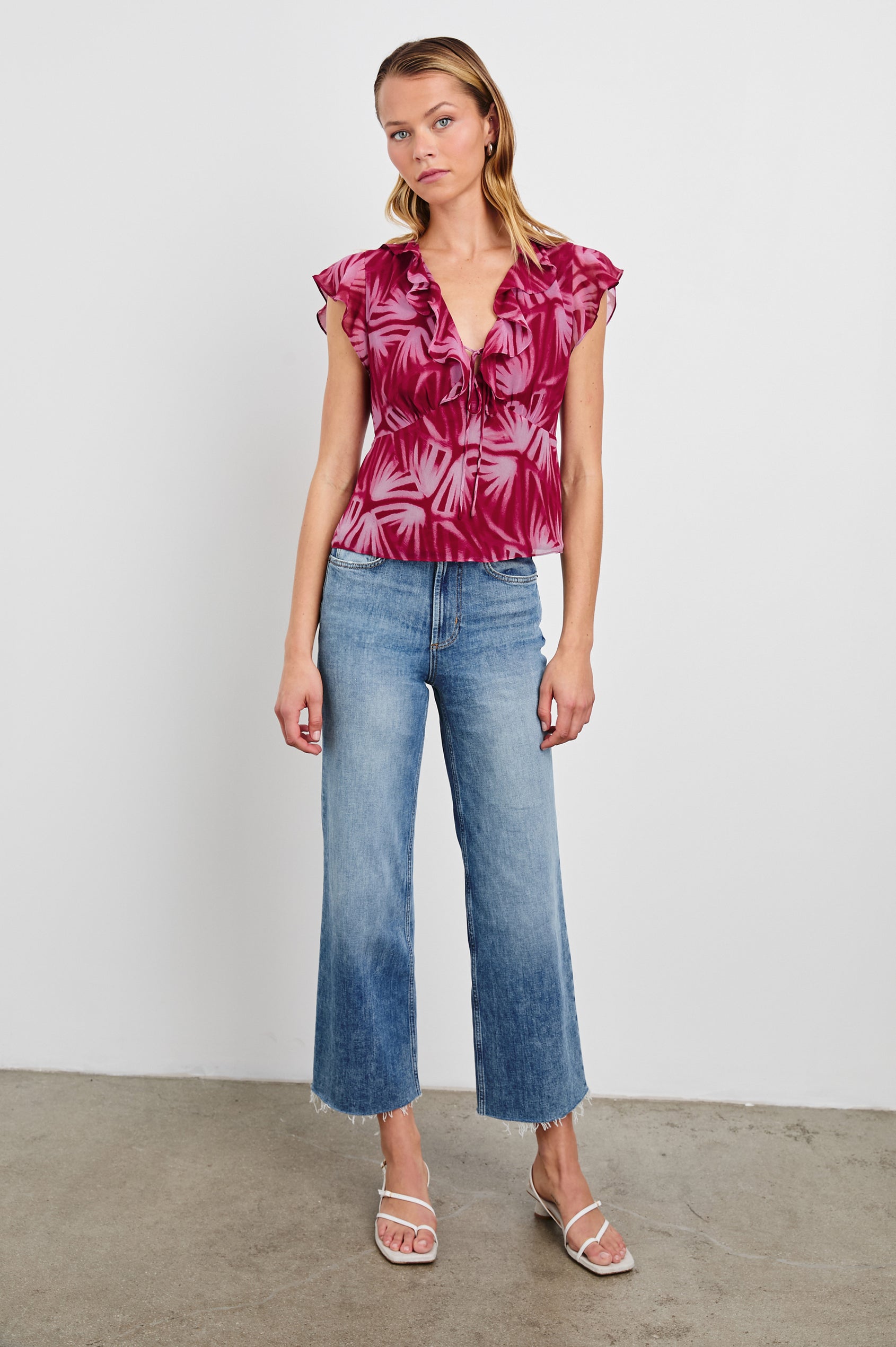 Carmine Top with Flutter Sleeves, Deep V Neck with a Tie, and a Ruffled Neckline in Bahia Colorway, a print with shades of pink - Front Full Body View Featured on Model