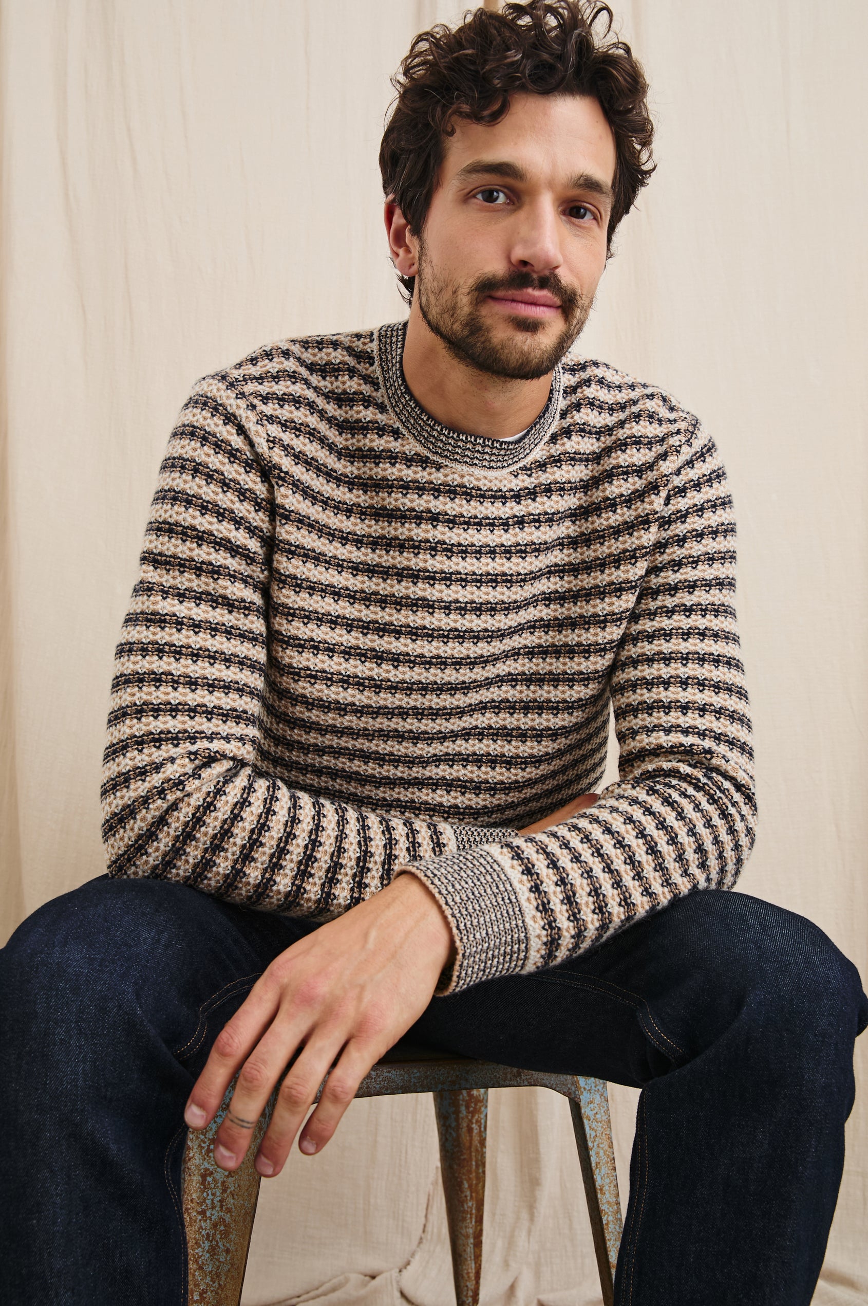 Carrick Long-Sleeve Sweater with a Crew Neck, Honeycomb Stitch, and Ribbed Trim in Navy Oat Stripe Colorway, Horizontal stripes - Front Full Body View Featured on Seated Model