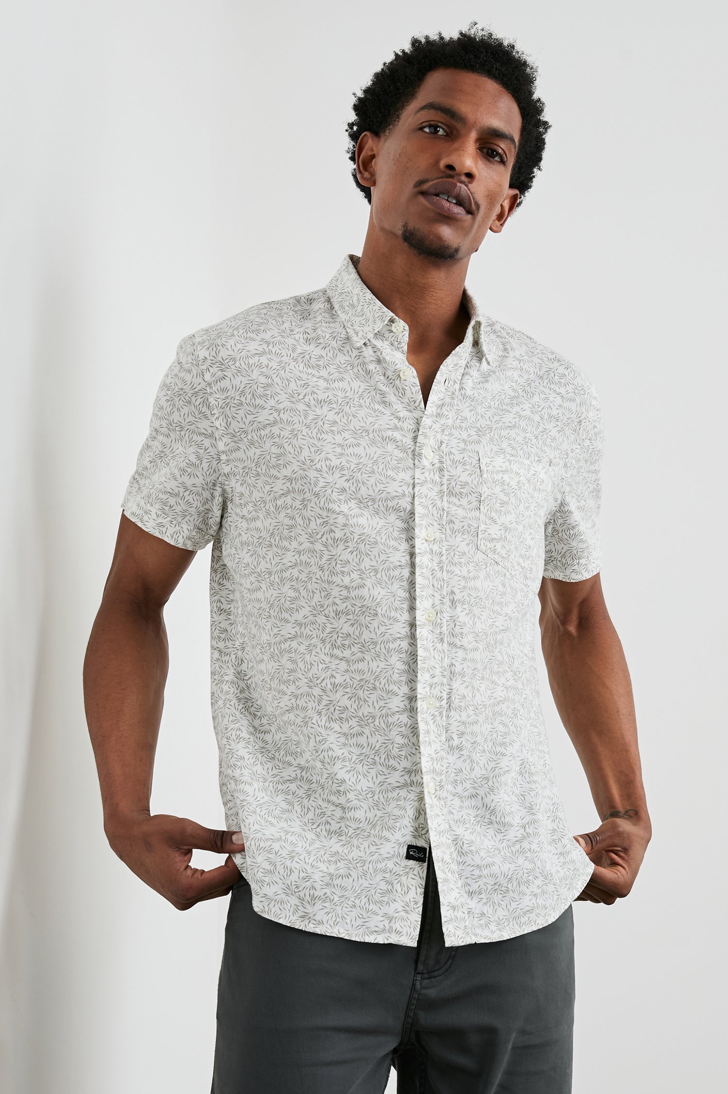 Carson Short Sleeve Button Up with a Chest Patch Pocket in Crop Circle White Colorway, Small Olive Leaves on White - Front View Featured on Model