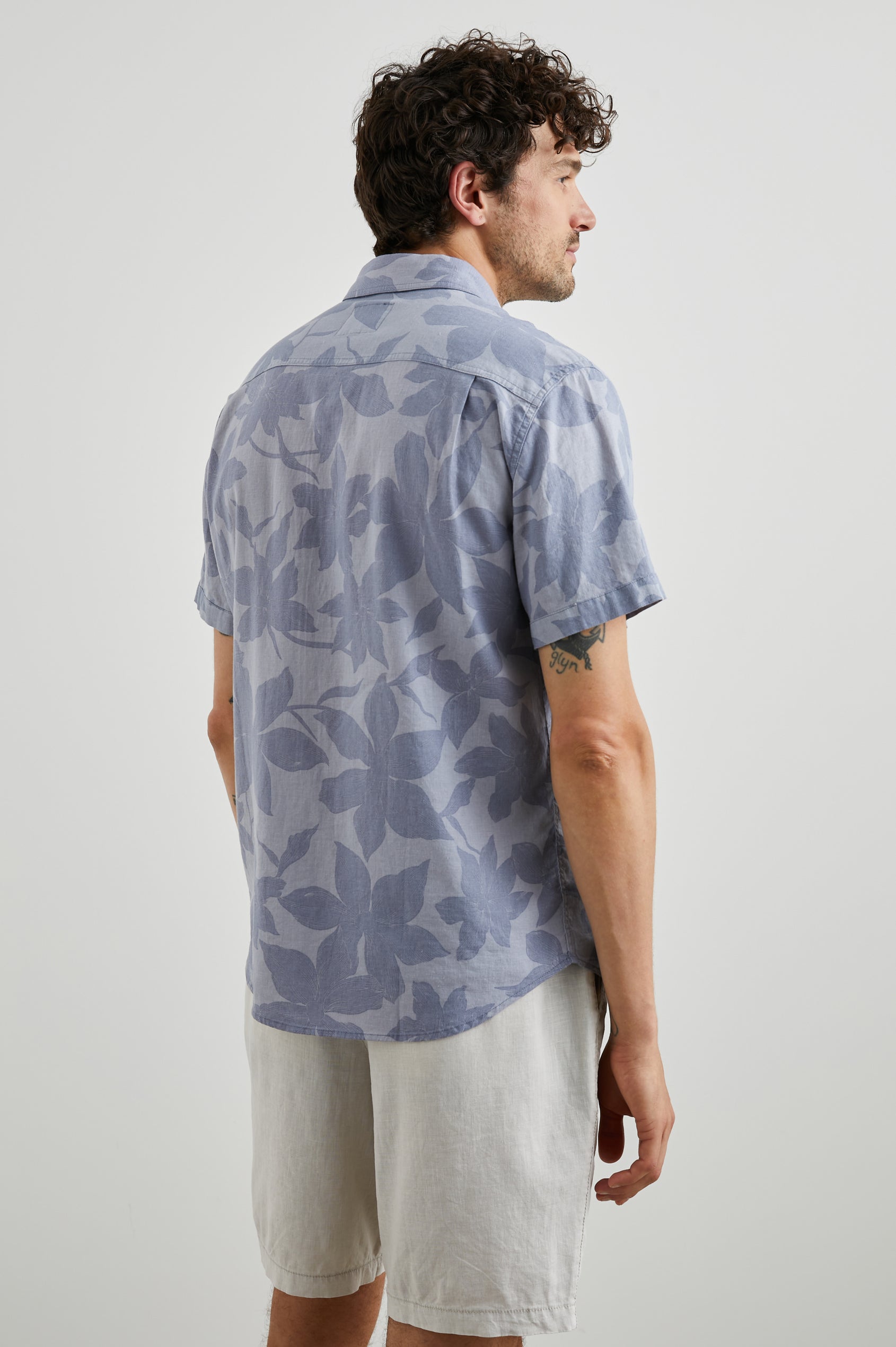 Carson Short Sleeve Button Up with a Chest Patch Pocket in Garden Sands Orchid Colorway, Blue Flowers on Light Blue - Back View Featured on Model