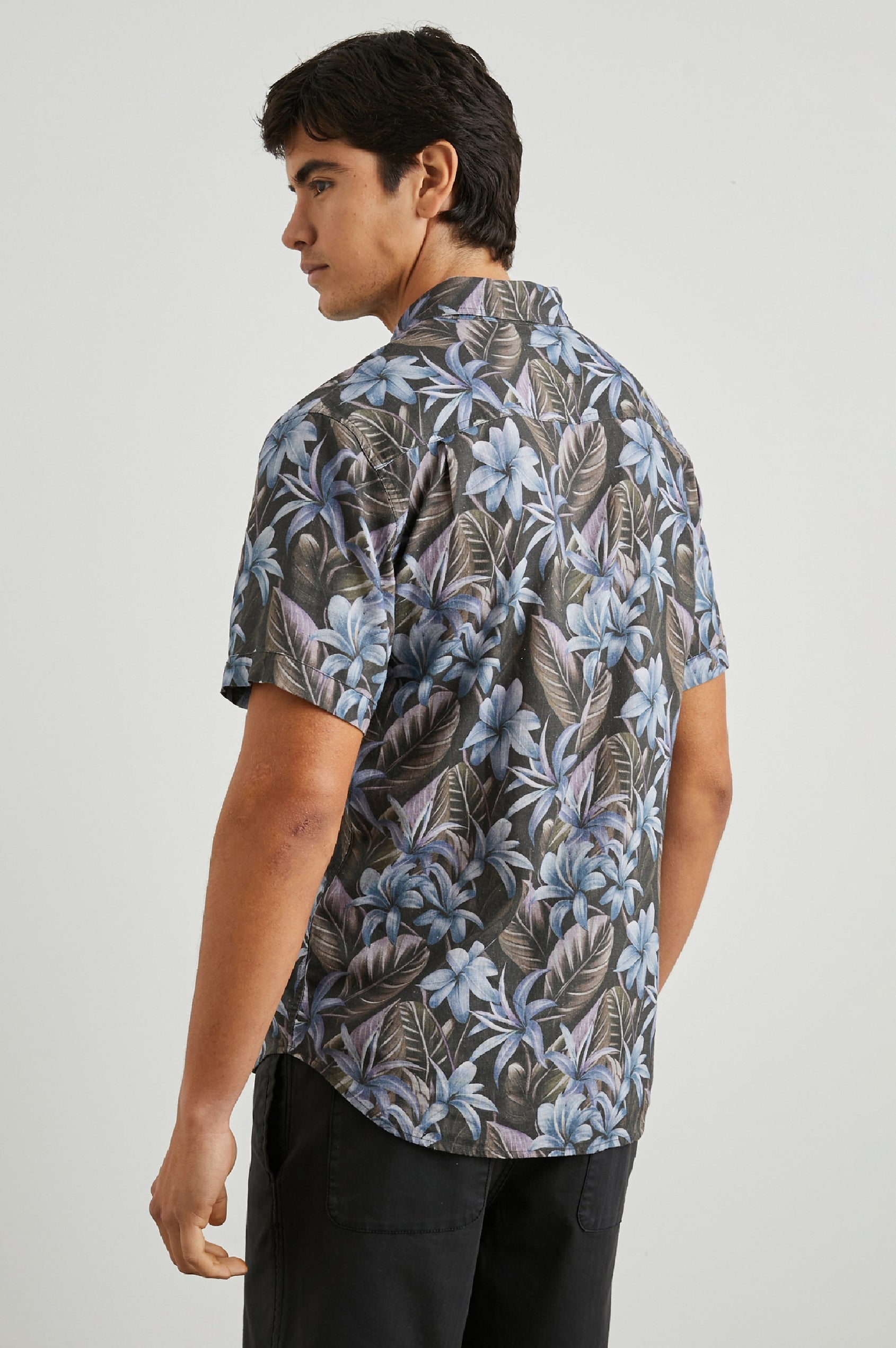Carson Short Sleeve Button Up with a Chest Patch Pocket in Jungle Garden Midnight Colorway, Flowers and Leaves in Blue and Olive on Midnight - Back View Featured on Model