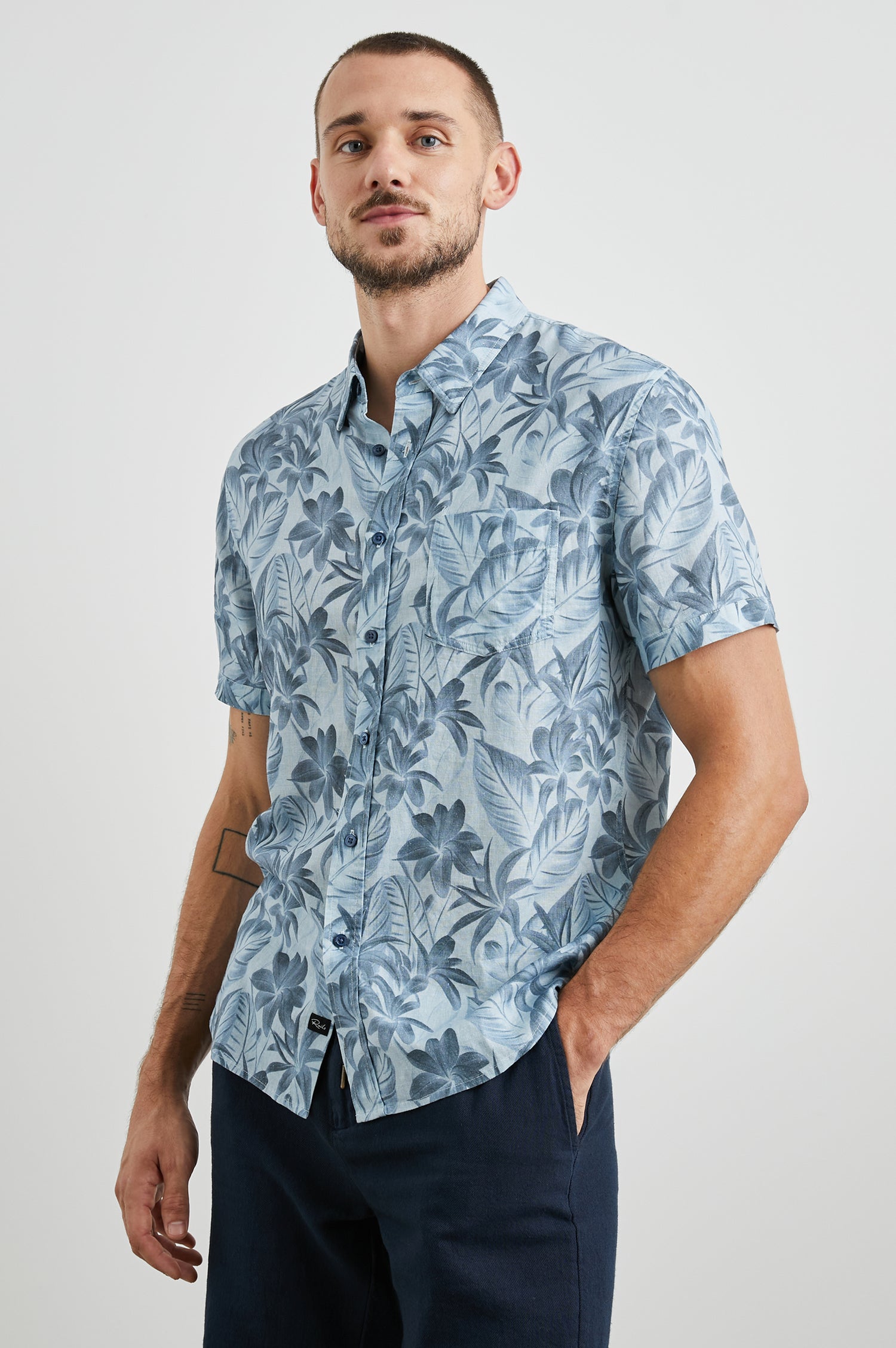 Carson Short Sleeve Button Up with a Chest Patch Pocket in Jungle Garden Reflection Colorway, Flowers and Leaves in Blues on Light Blue - Front View Featured on Model
