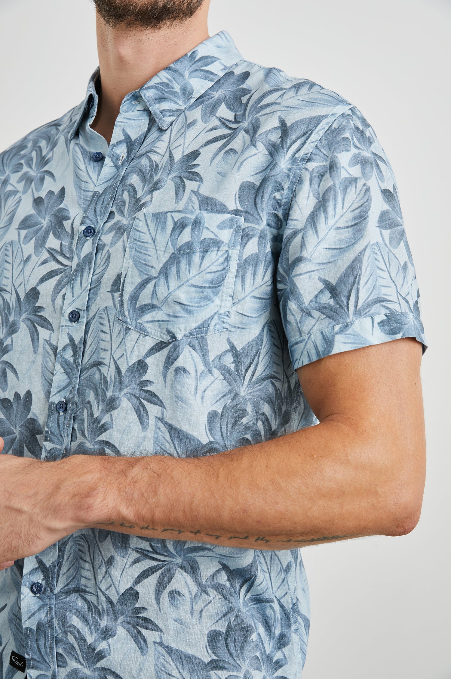 Carson Short Sleeve Button Up with a Chest Patch Pocket in Jungle Garden Reflection Colorway, Flowers and Leaves in Blues on Light Blue - Front View Featured on Model