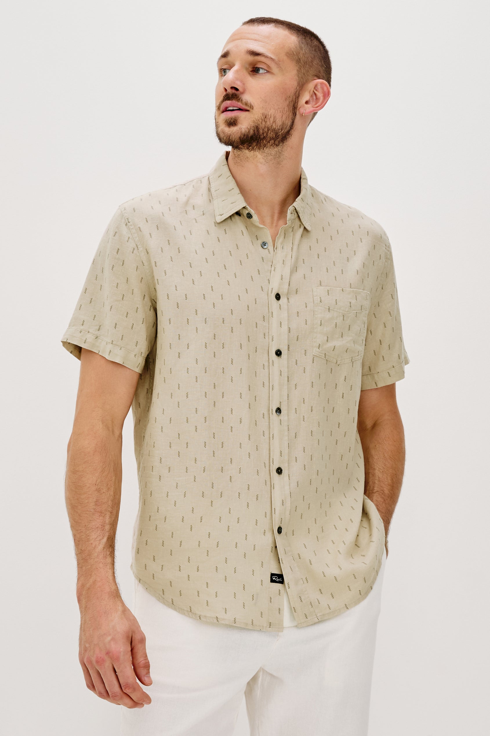 Carson linen short sleeve button down with a collar and front chest pocket in Louis Leaf Khaki colorway - front view on model looking to side