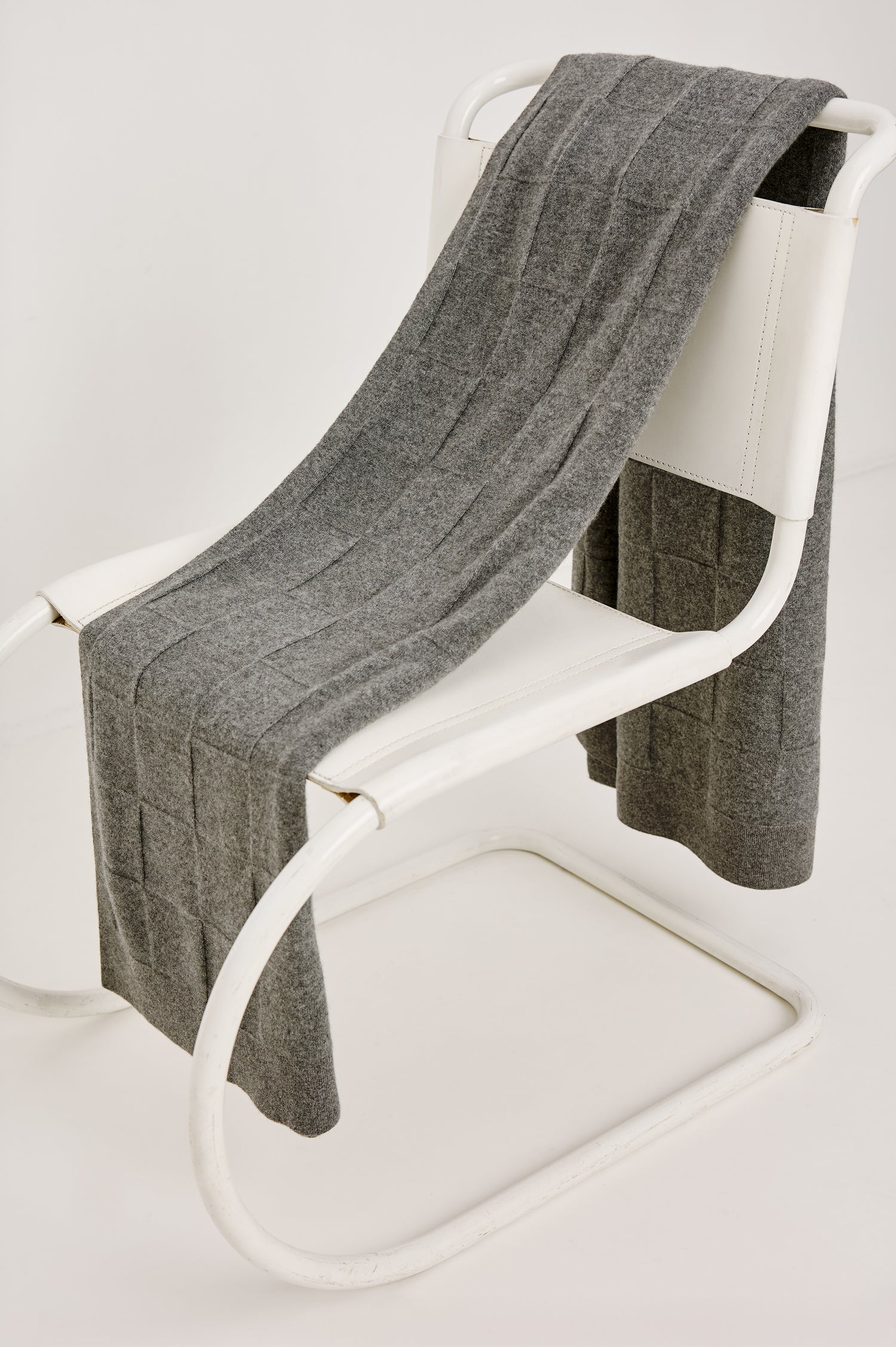 Cashmere throw in grey colorway. Draped on a chair.