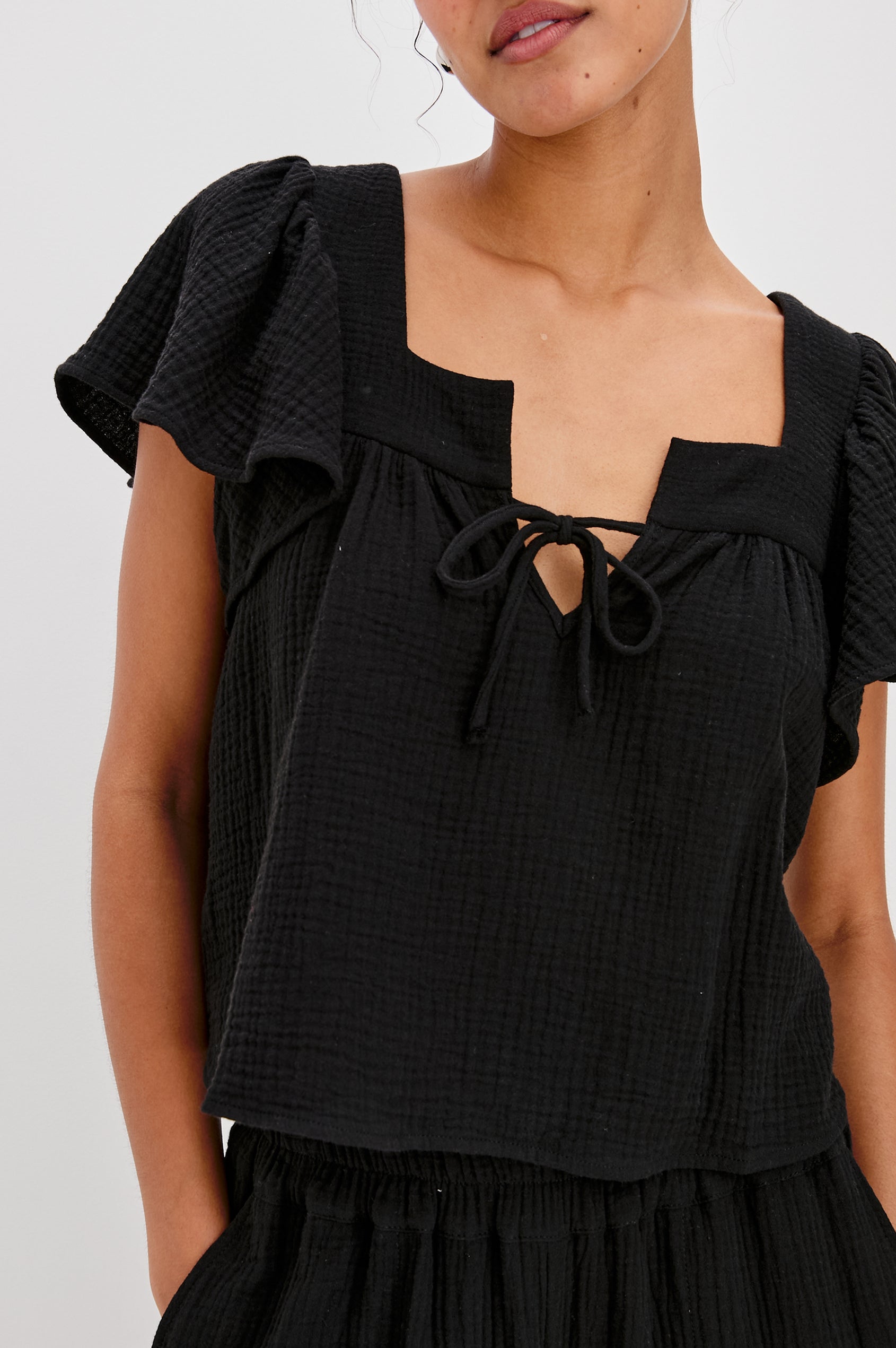Casie Square Neck Top with Short Flutter Sleeves, V-Cut Center Front with Self Tie in Black Colorway. Front View Shown on Model.
