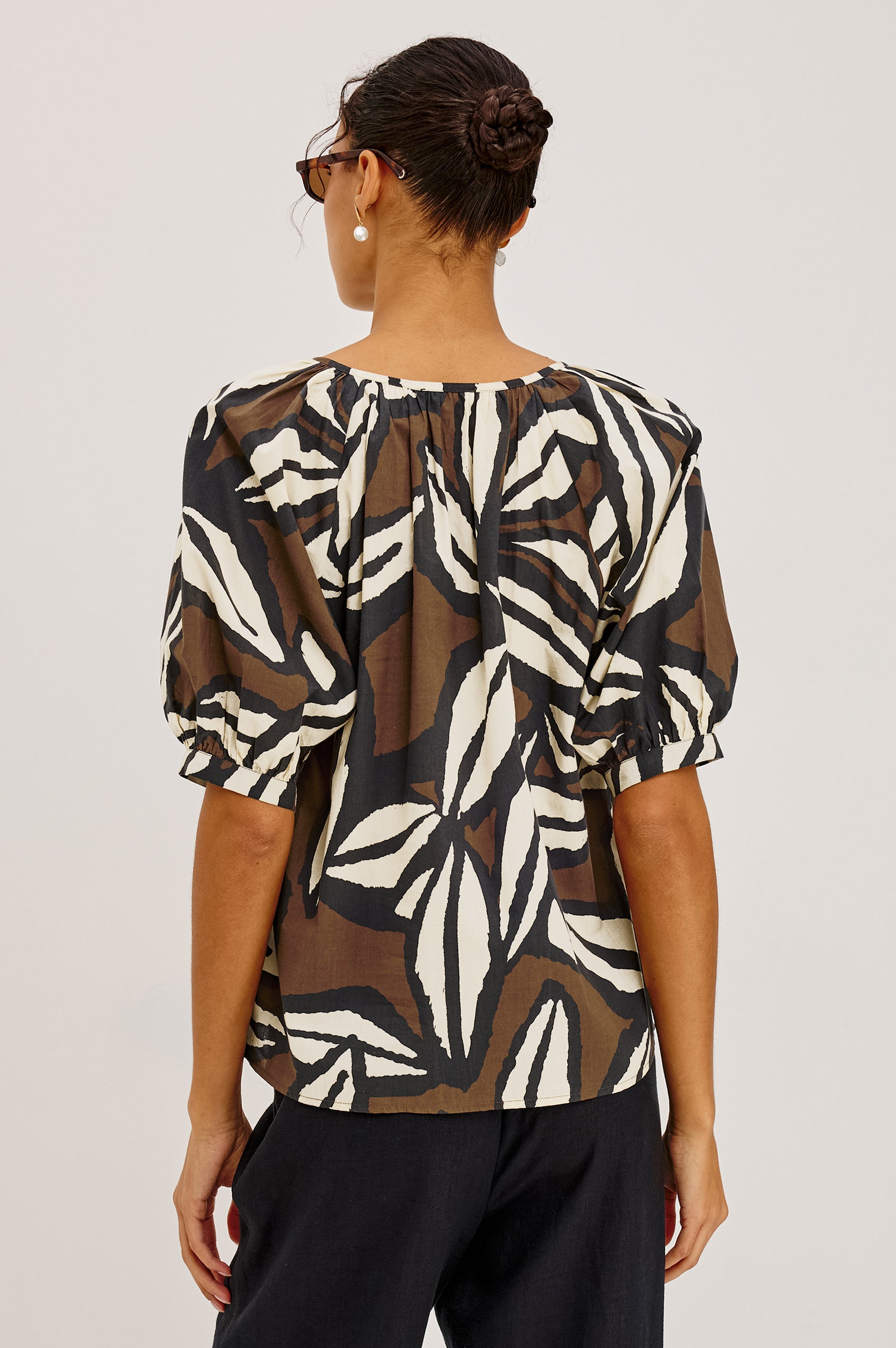 Catalene Peasant Blouse in Cotton Voile With Self-Tie V-Neckline, Loose Fit, and Short Puff Sleeves in Cocoa Floral Colorway - Upper Body Back View Featured on Model