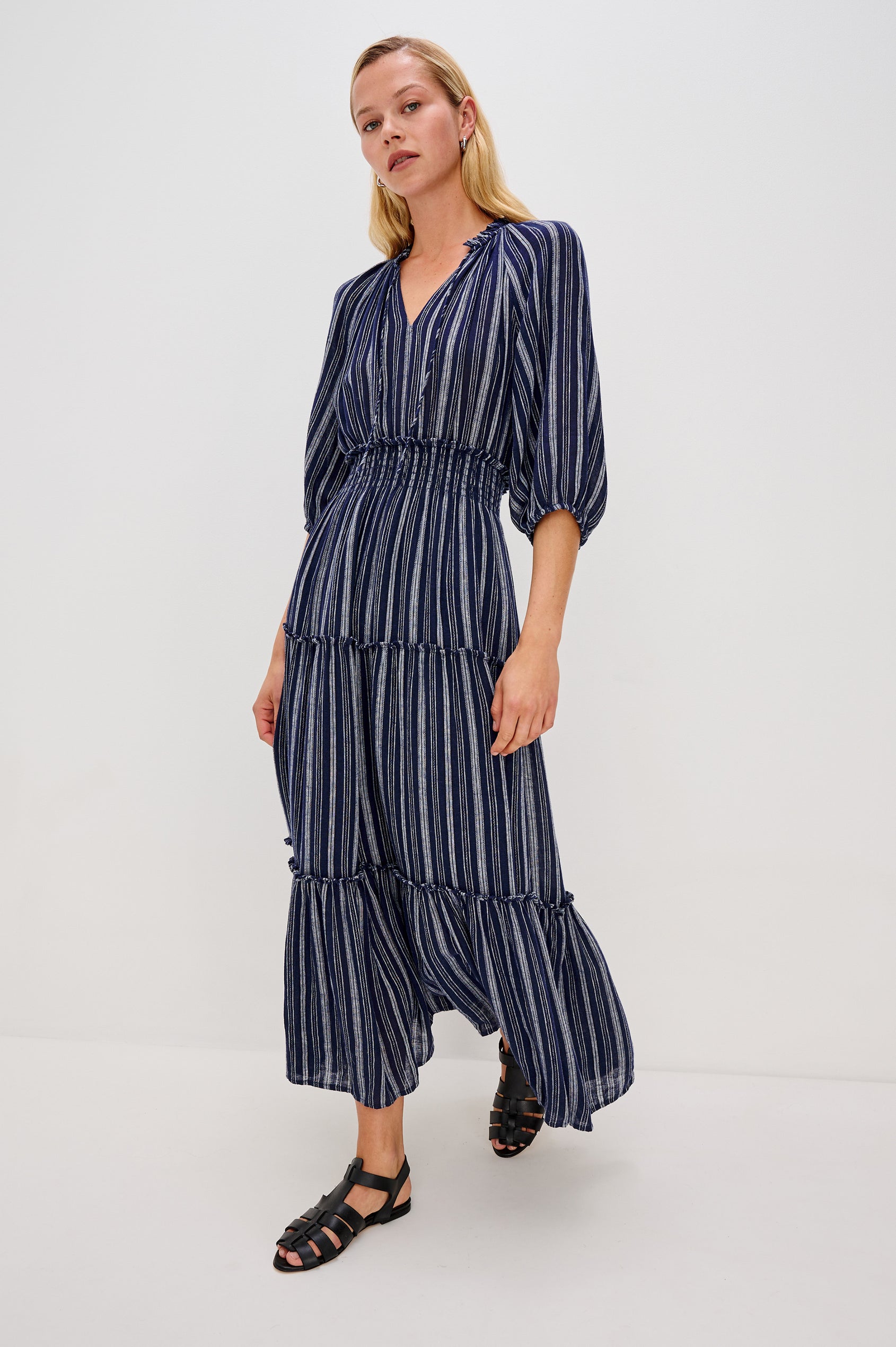 Caterine Maxi Dress with Mid-length Sleeves, a V neck, a Shirred Collar with a tie, a Smocked Waist, and a Tiered Skirt in Roche Stripe Colorway - full body front view, model in motion