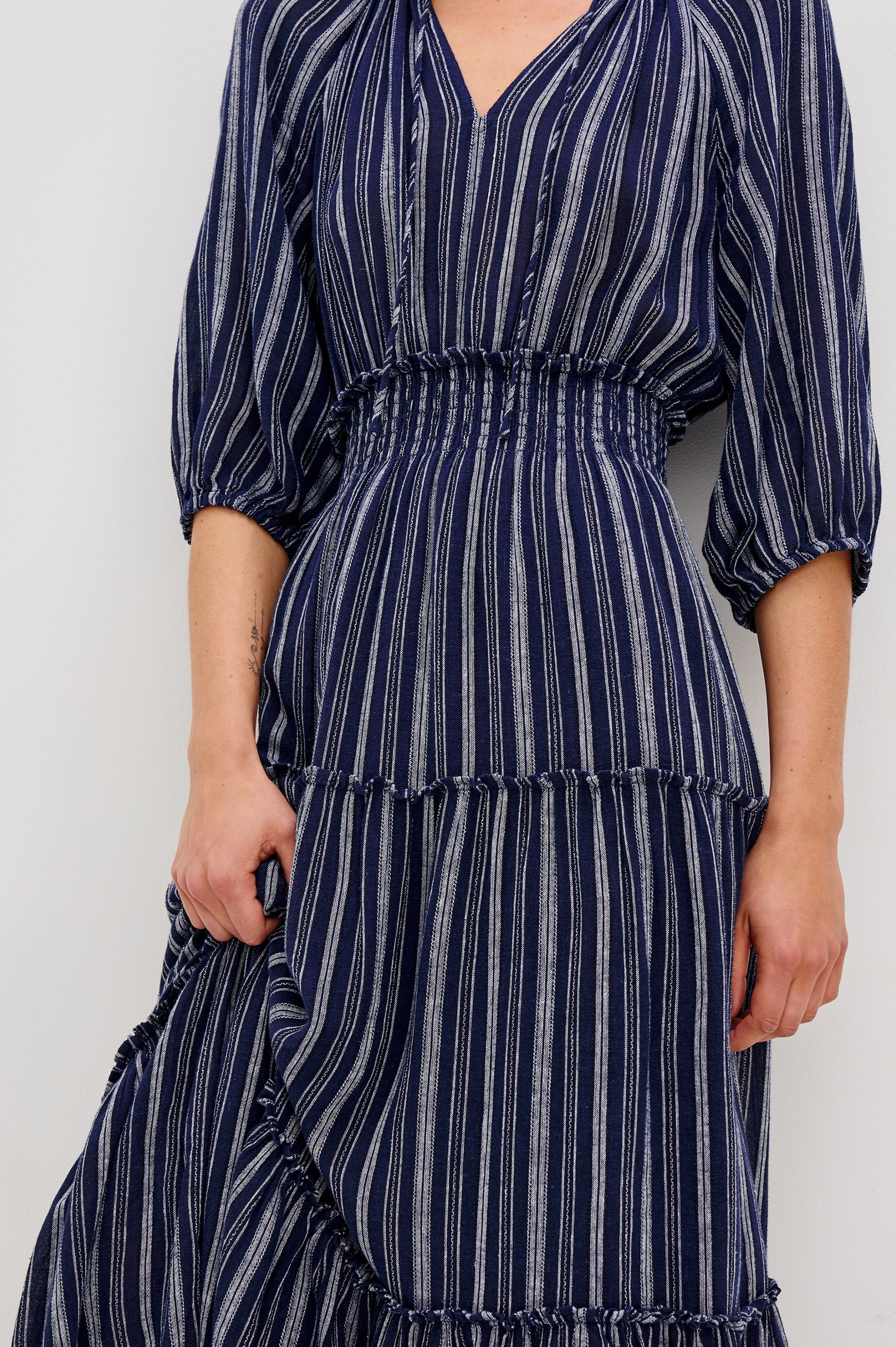 Caterine Maxi Dress with Mid-length Sleeves, a V neck, a Shirred Collar with a tie, a Smocked Waist, and a Tiered Skirt in Roche Stripe Colorway - close up of details on model