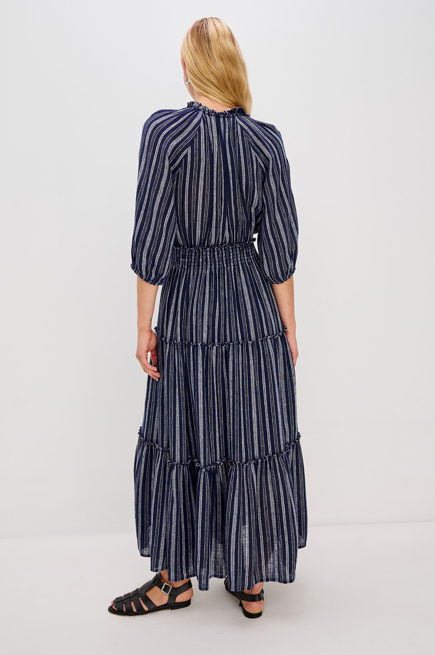Caterine Maxi Dress with Mid-length Sleeves, a V neck, a Shirred Collar with a tie, a Smocked Waist, and a Tiered Skirt in Roche Stripe Colorway - back view on model