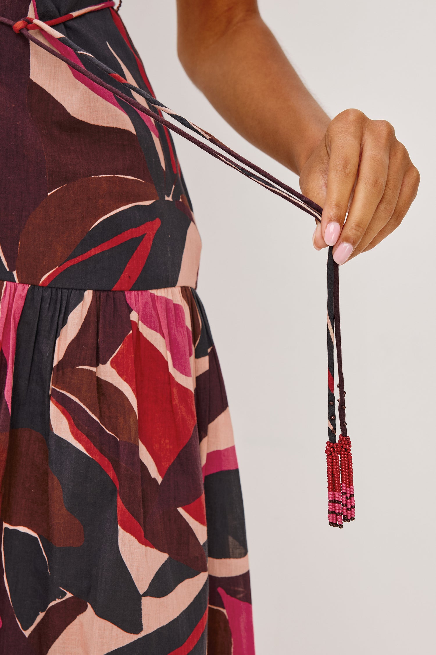 Cecilie Midi Dress in Cotton Voile With One-Shoulder Neckline, Adjustable Waist Ties With Beaded Tassels, Dropwaist Tier Detail, Fully Lined, and Side Zipper Closure in Paradise Colorway - Close Up View Featured on Model