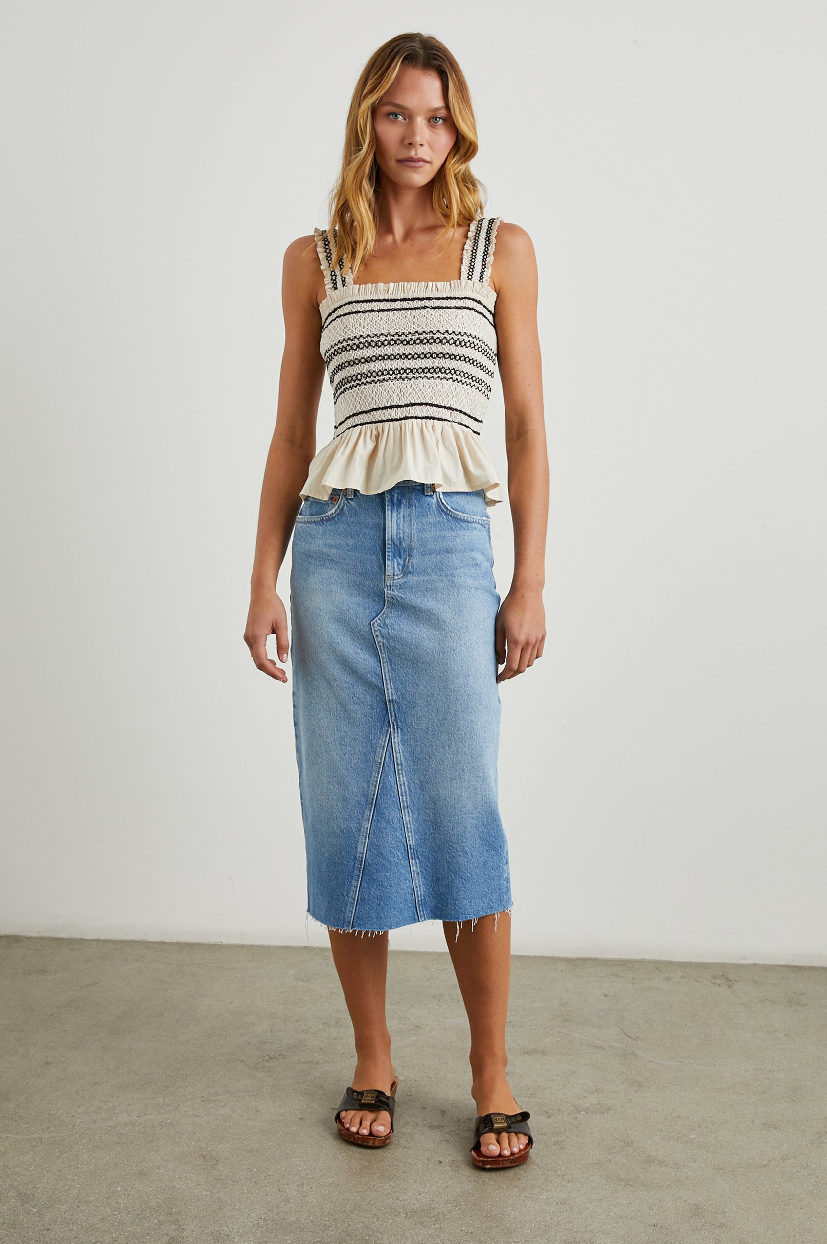 Cecily Tank Top with a Smocked Bodice, a Frilled Hem, a Square Neckline, and Ruffles along the Neckline and Straps in Flax Colorway, with Black Decorative Stitching - Front Full Body View Featured on Model  