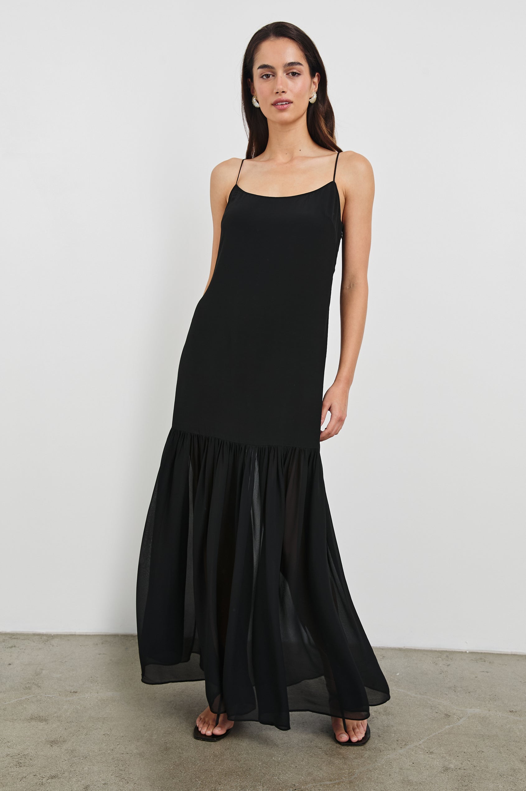 Chandra Maxi Tank Dress with Spaghetti Straps and a Contrast Semi Sheer Fabric Gathered Hem in Black Colorway. Full Body Front View Shown on Model.