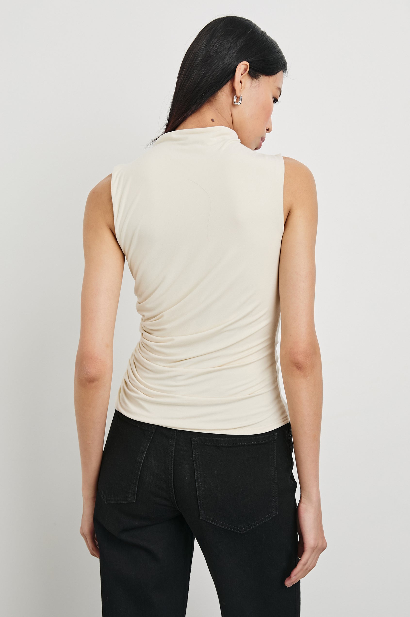Christen Sleeveless Top with a Mock Neck and Ruching Along One Side Seam in Ivory Colorway - Back View Featured on Model