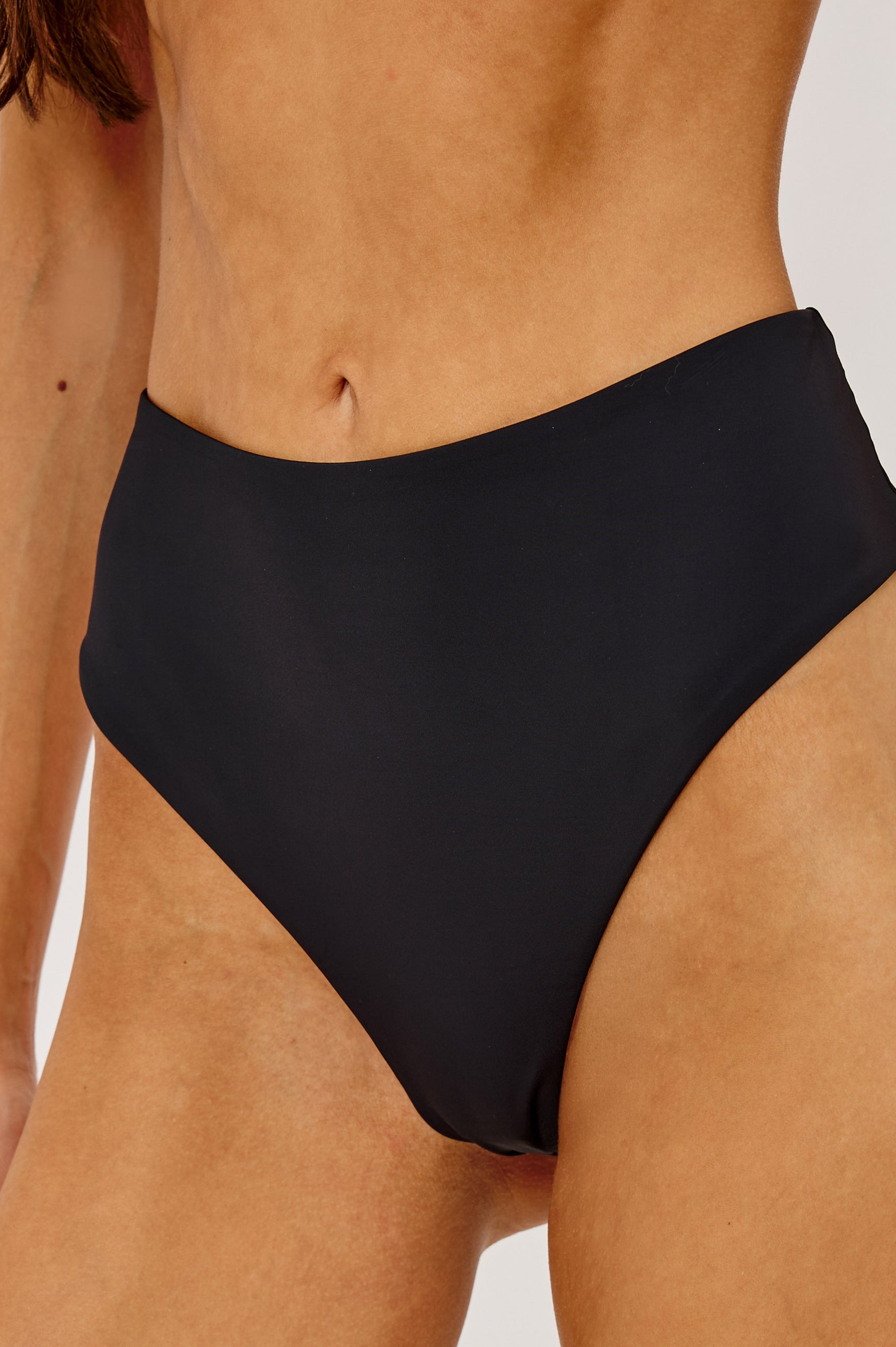 Cielo Bikini Bottom With High Waist, High-Cut Legs, and Cheeky Rear Coverage in Black Colorway - Lower Body Front View Featured on Model