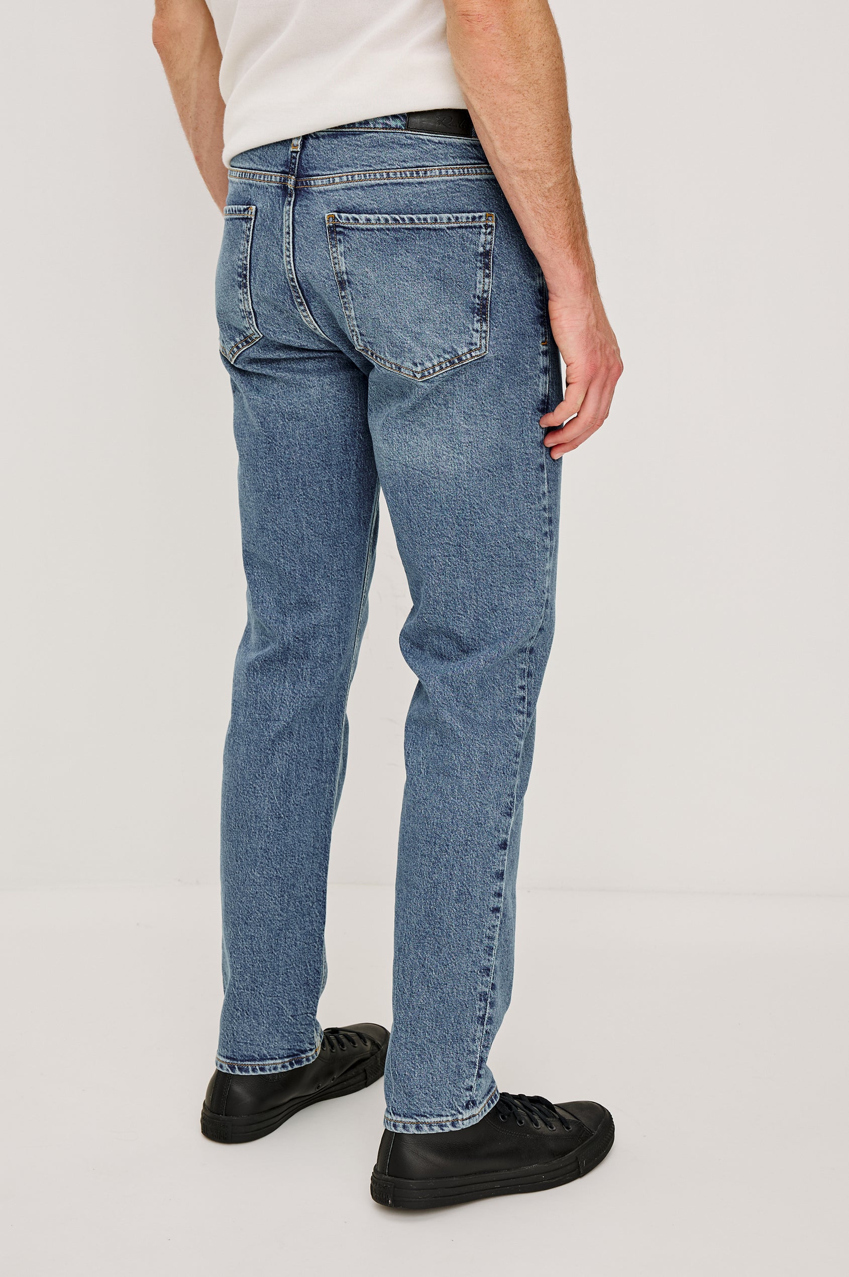Clayton Slim Straight is a Classic 5-Pocket Jean in Heritage Indigo Colorway, a Medium Blue Wash. Back View Featured on Model.