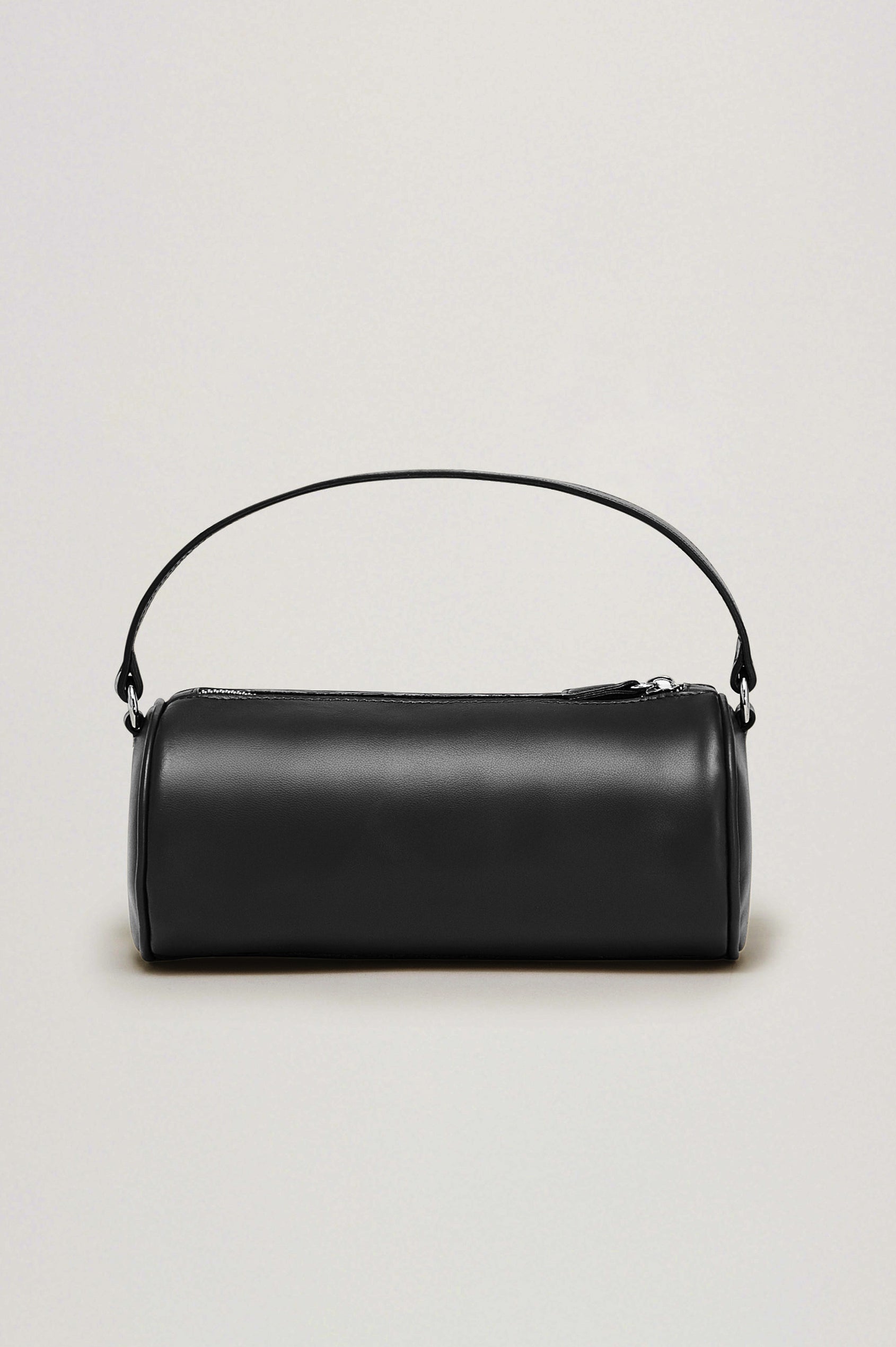 The Como is a mini barrel bag, made from smooth leather with a fixed top strap, a removable and adjustable buckled crossbody strap, a top zip, a side-embossed logo, and a branded interior label, in Black Leather colorway. Front view featured.