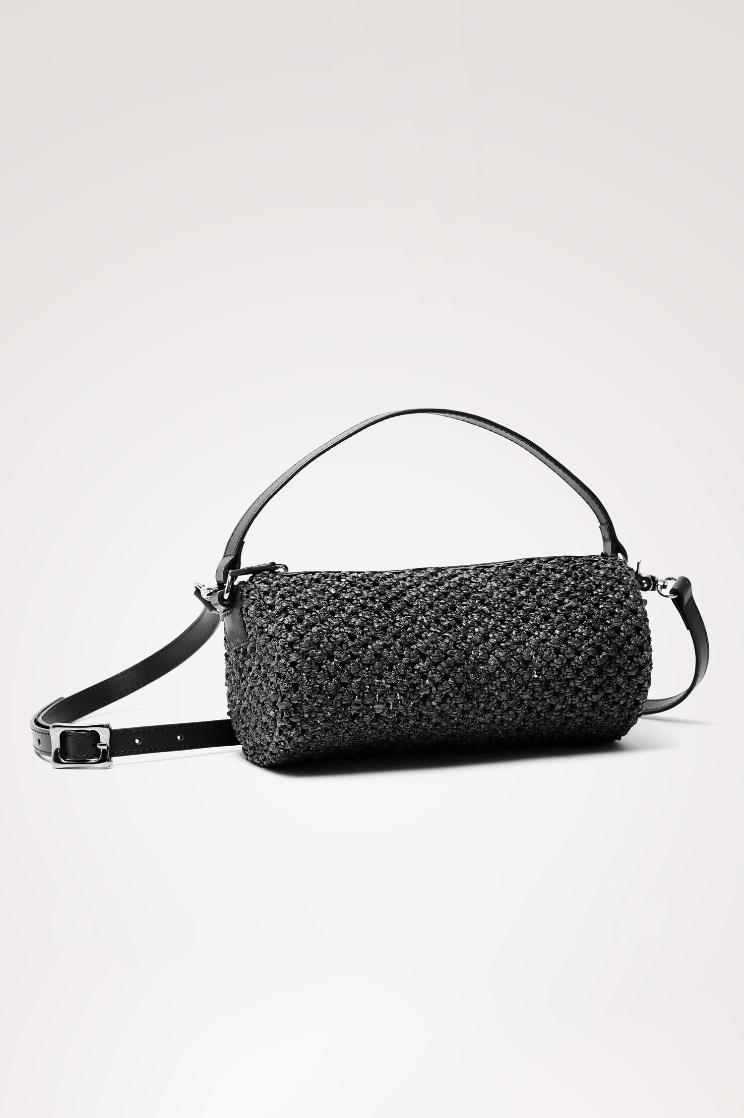Como Mini Barrel Bag in Woven Raffia With Top Strap, Removable and Adjustable Crossbody Strap, and Top Zip in Black Raffia Colorway - Front View Featured