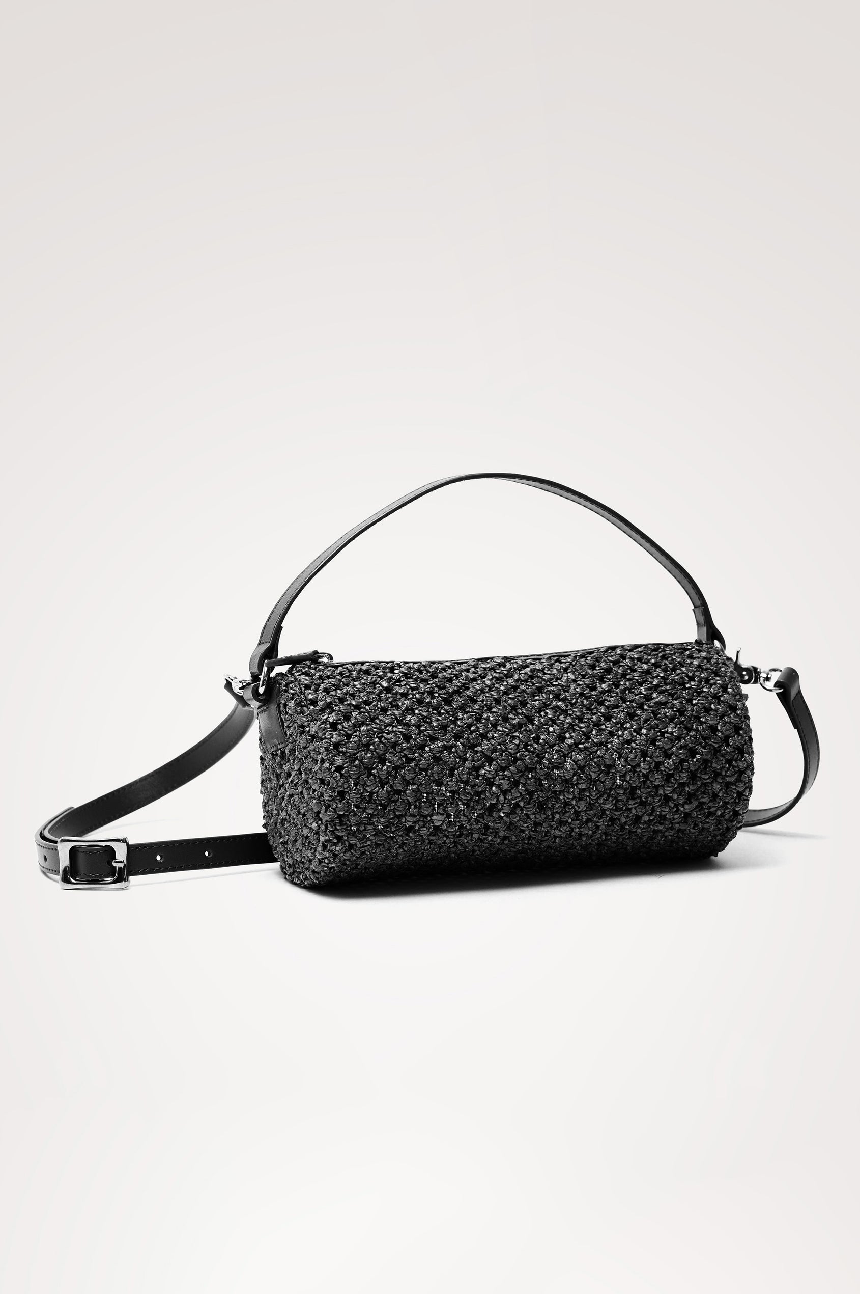 Como Mini Barrel Bag in Woven Raffia With Top Strap, Removable and Adjustable Crossbody Strap, and Top Zip in Black Raffia Colorway - Front View Featured