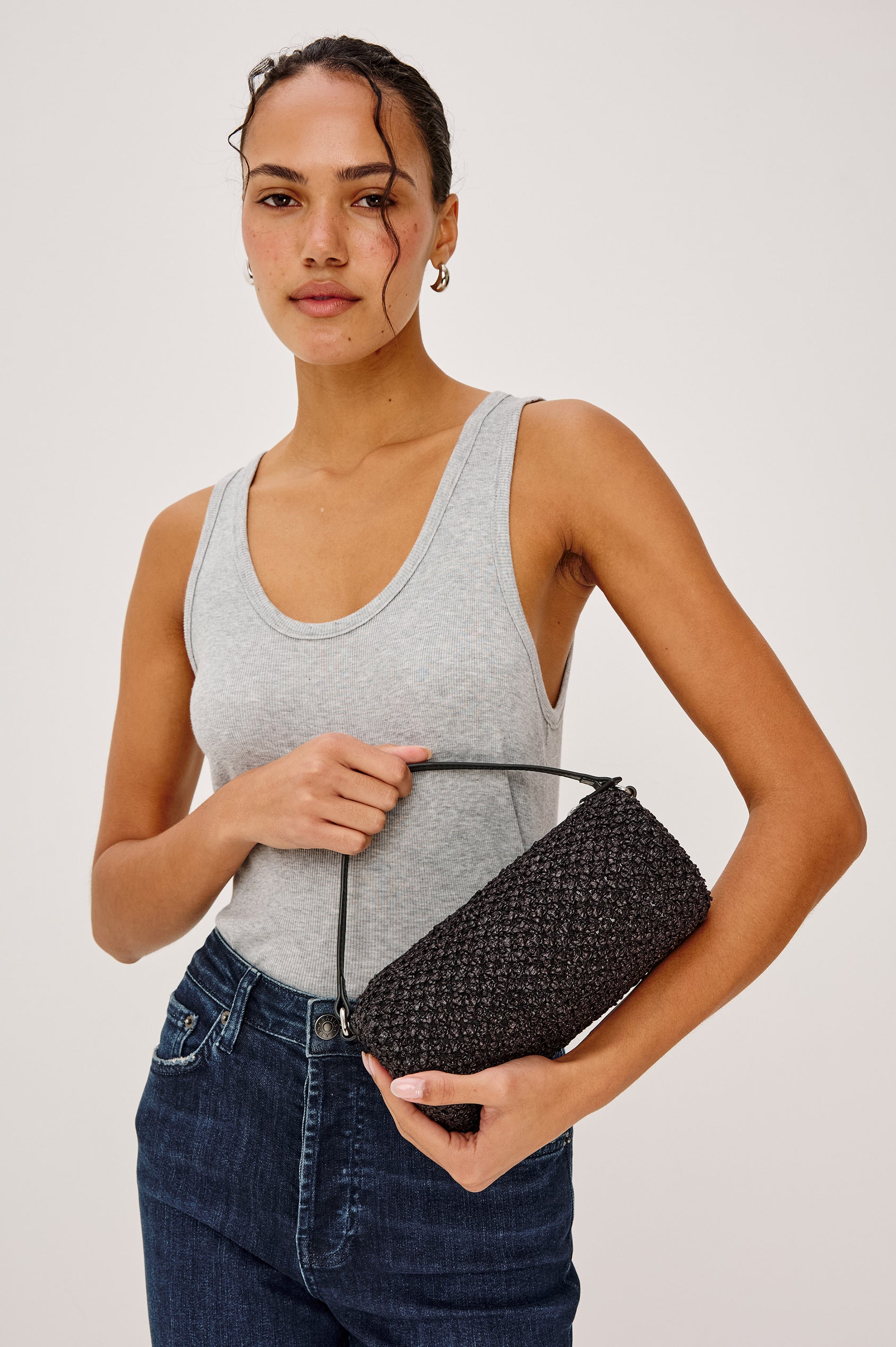 Como Mini Barrel Bag in Woven Raffia With Top Strap, Removable and Adjustable Crossbody Strap, and Top Zip in Black Raffia Colorway - Front Upper Body View Featured on Model