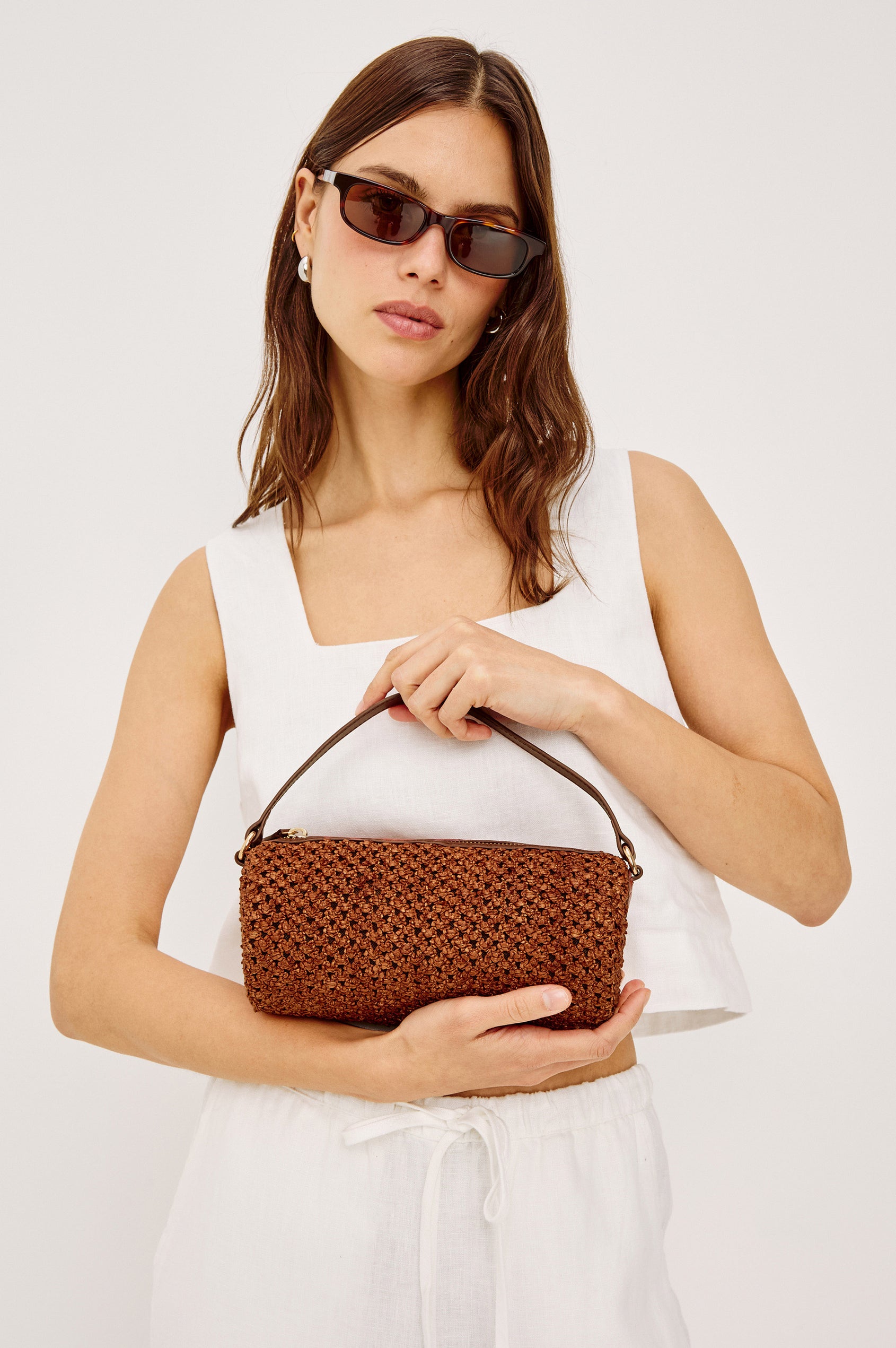 Como Mini Barrel Bag in Woven Raffia With Top Strap, Removable and Adjustable Crossbody Strap, and Top Zip in Cognac Raffia Colorway - Upper Body View Featured on Model