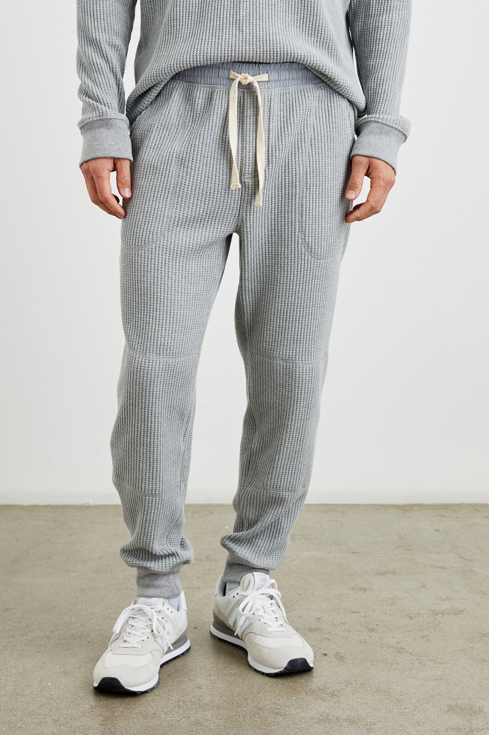 Cooper Waffle Thermal Pants with an Elastic Drawstring Waist, Two Teardrop Front Pockets, Two Back Welt Pockets, Reinforced Knee Patches and Elastic Cuffs in Heather Grey Colorway - Front View Featured on Model