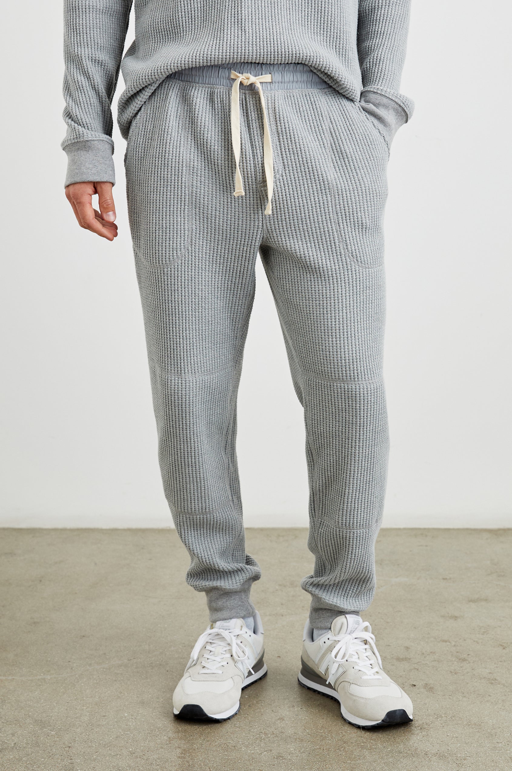 Cooper Waffle Thermal Pants with an Elastic Drawstring Waist, Two Teardrop Front Pockets, Two Back Welt Pockets, Reinforced Knee Patches and Elastic Cuffs in Heather Grey Colorway - Front View Featured on Model
