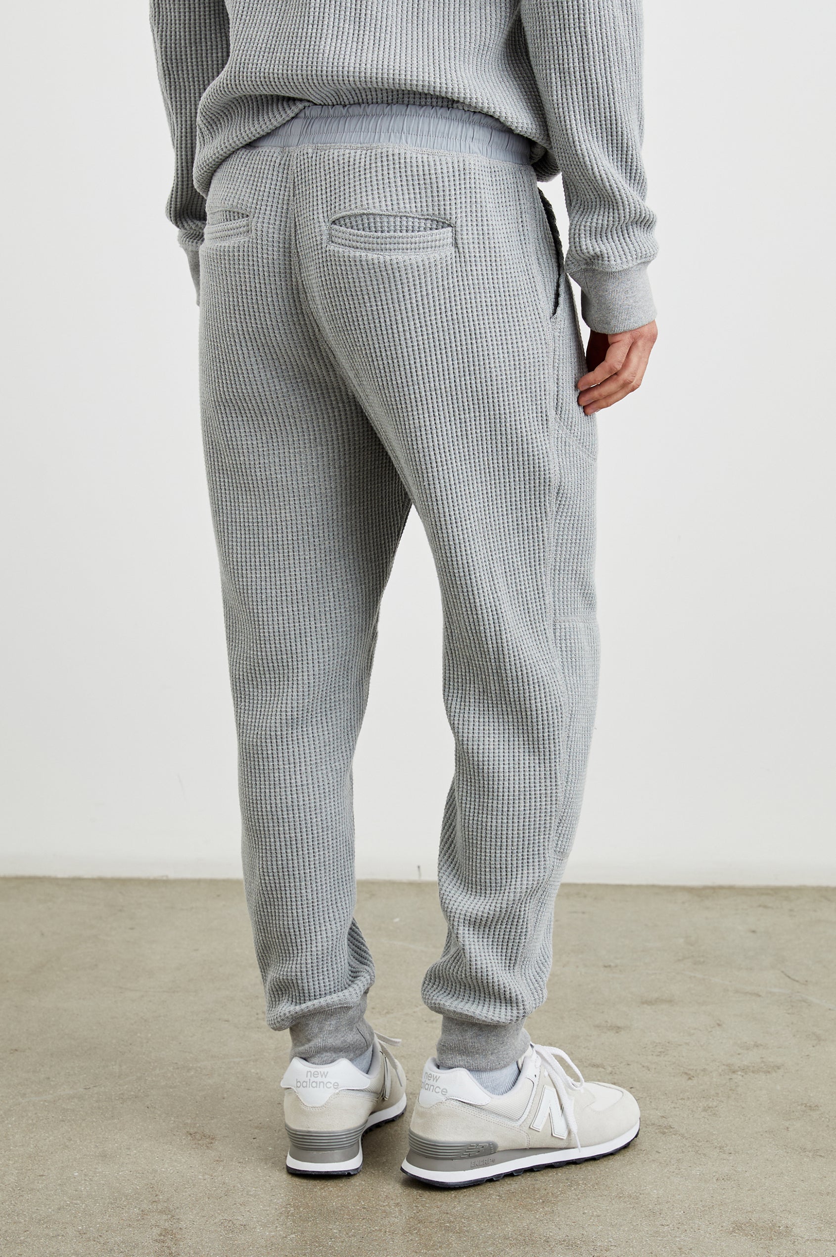 Cooper Waffle Thermal Pants with an Elastic Drawstring Waist, Two Teardrop Front Pockets, Two Back Welt Pockets, Reinforced Knee Patches and Elastic Cuffs in Heather Grey Colorway - Back View Featured on Model