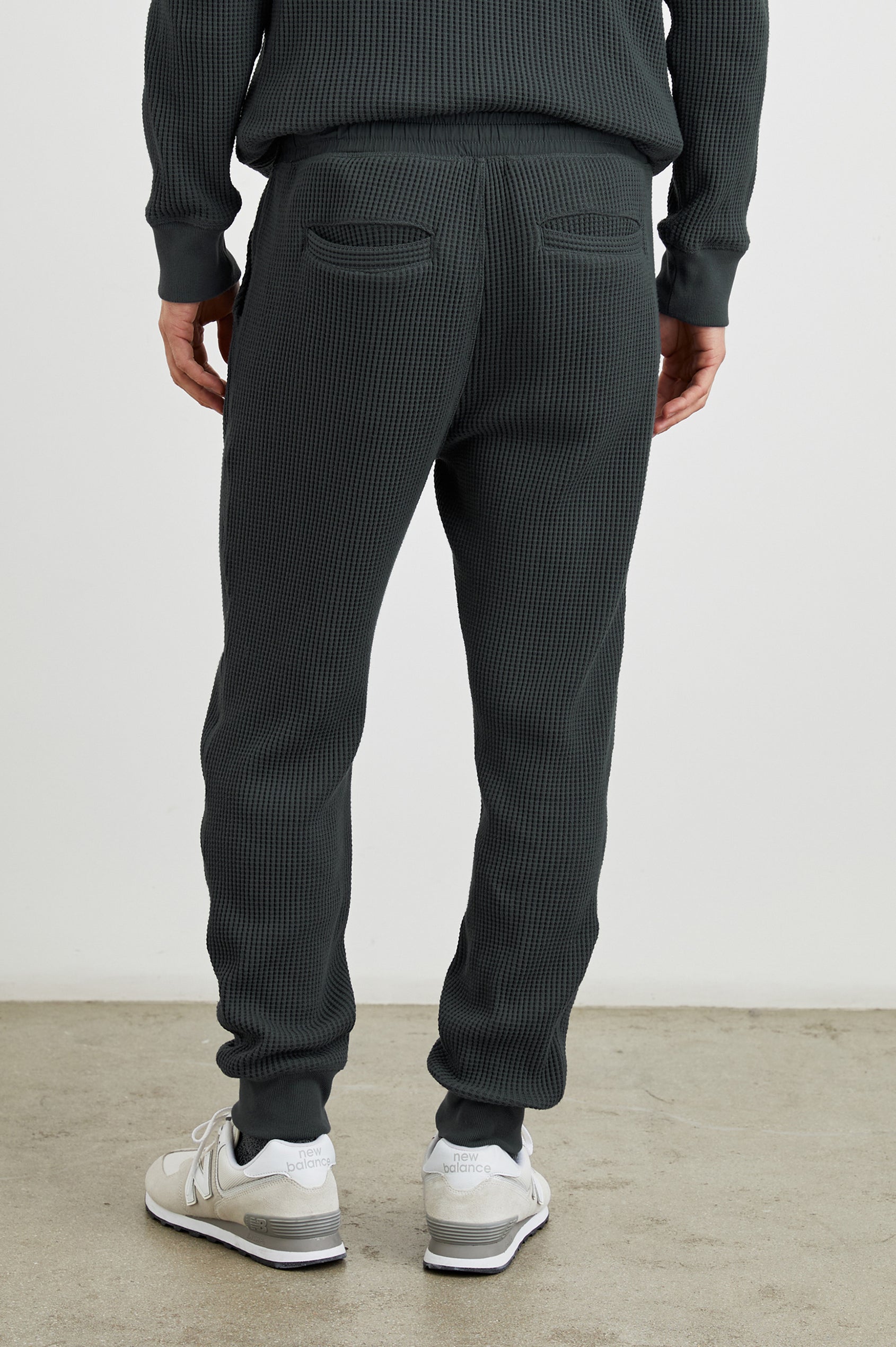 Cooper Waffle Thermal Pants with an Elastic Drawstring Waist, Two Teardrop Front Pockets, Two Back Welt Pockets, Reinforced Knee Patches and Elastic Cuffs in Ink Colorway - Back View Featured on Model
