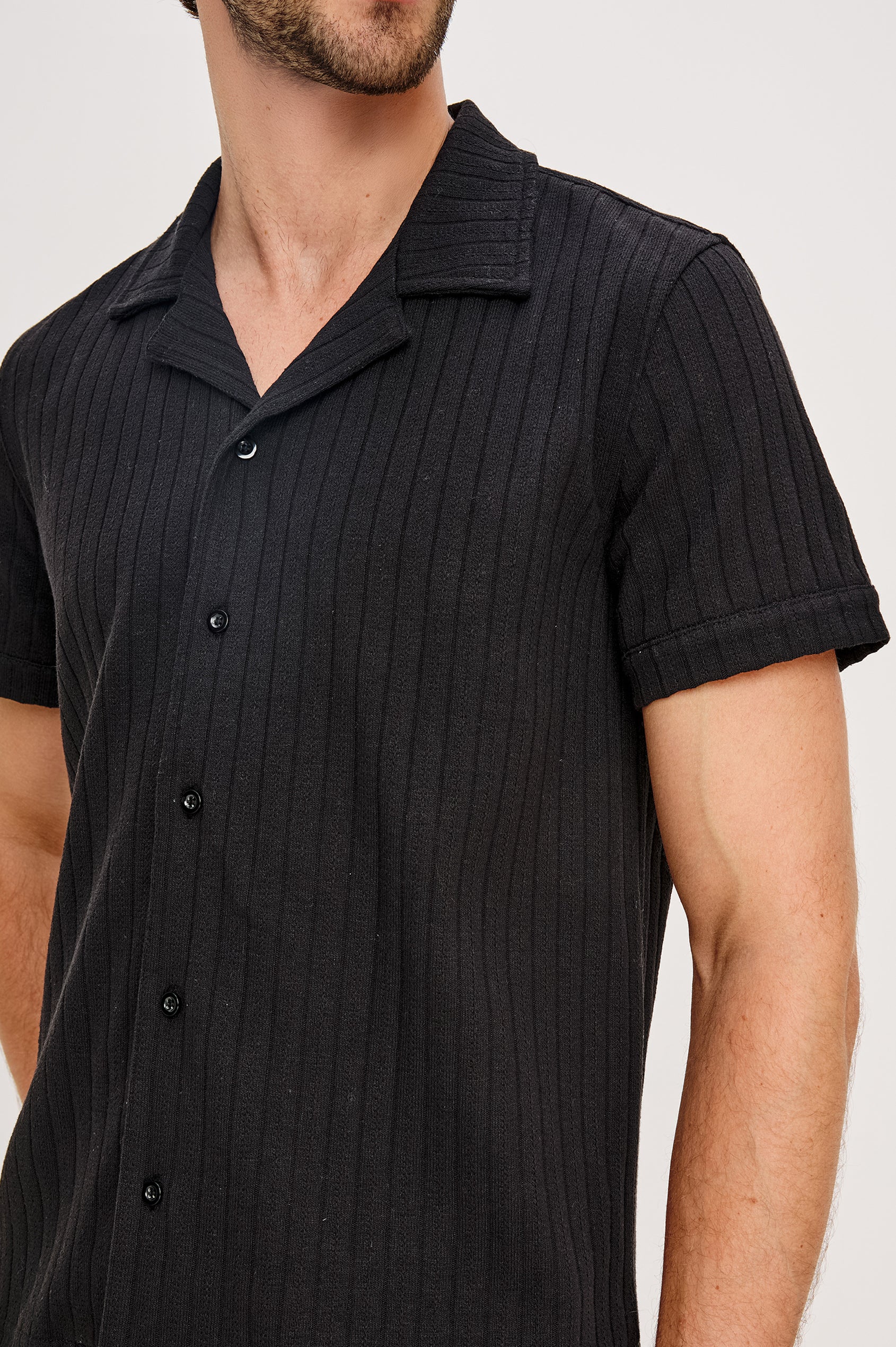 Corrin is a short sleeve camp style shirt with a notched lapel in Black colorway. Front detail view featured on model.